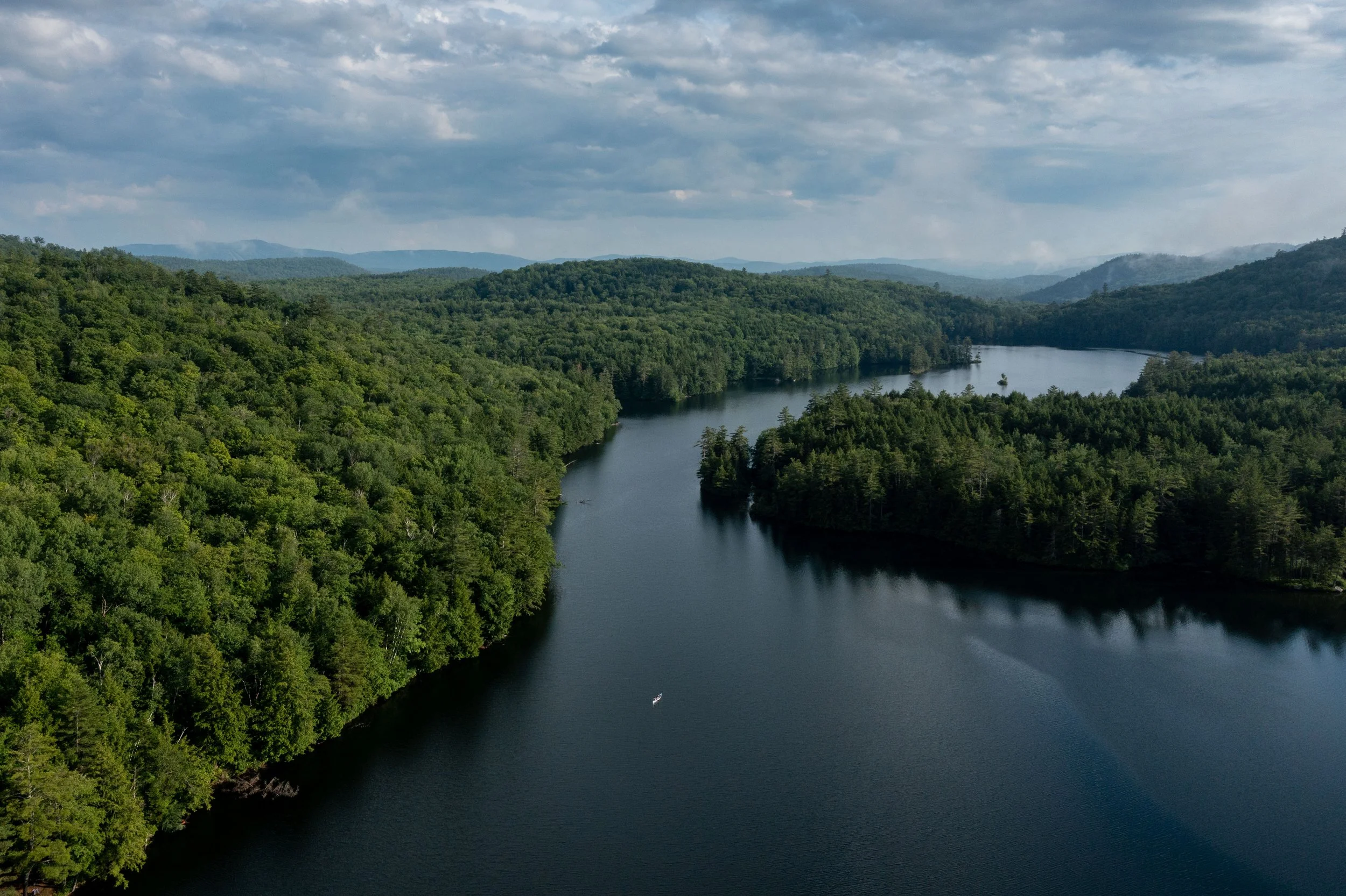 Aerial view of a winding river surrounded by lush green forests under a cloudy sky.