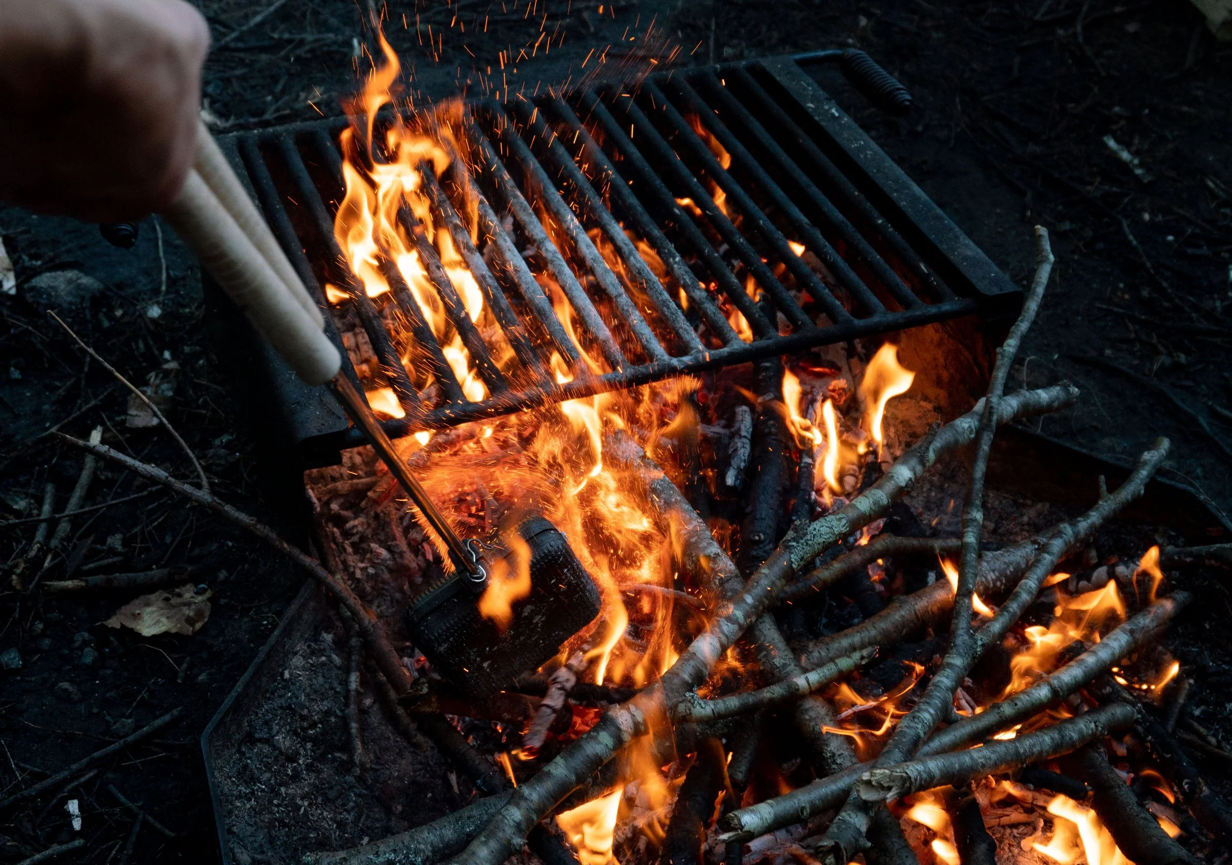 Person using a guitar amplifier as a grill over an open fire with burning wood and sticks surrounding it.