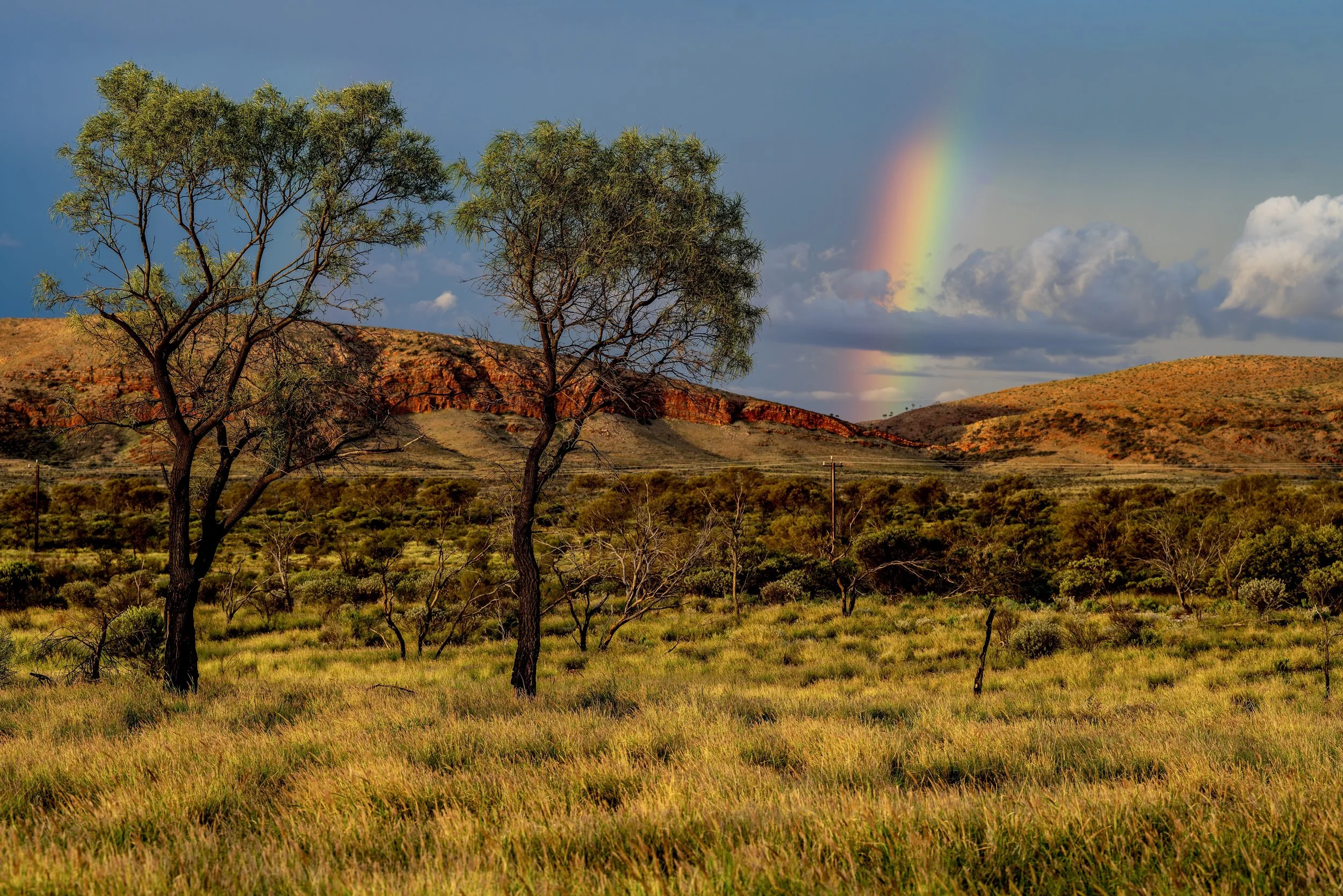G072- 10th of December 2024 18:49- Golden hour light with showers and a rainbow north of Purli Yurliya (Rawlinson Ranges).