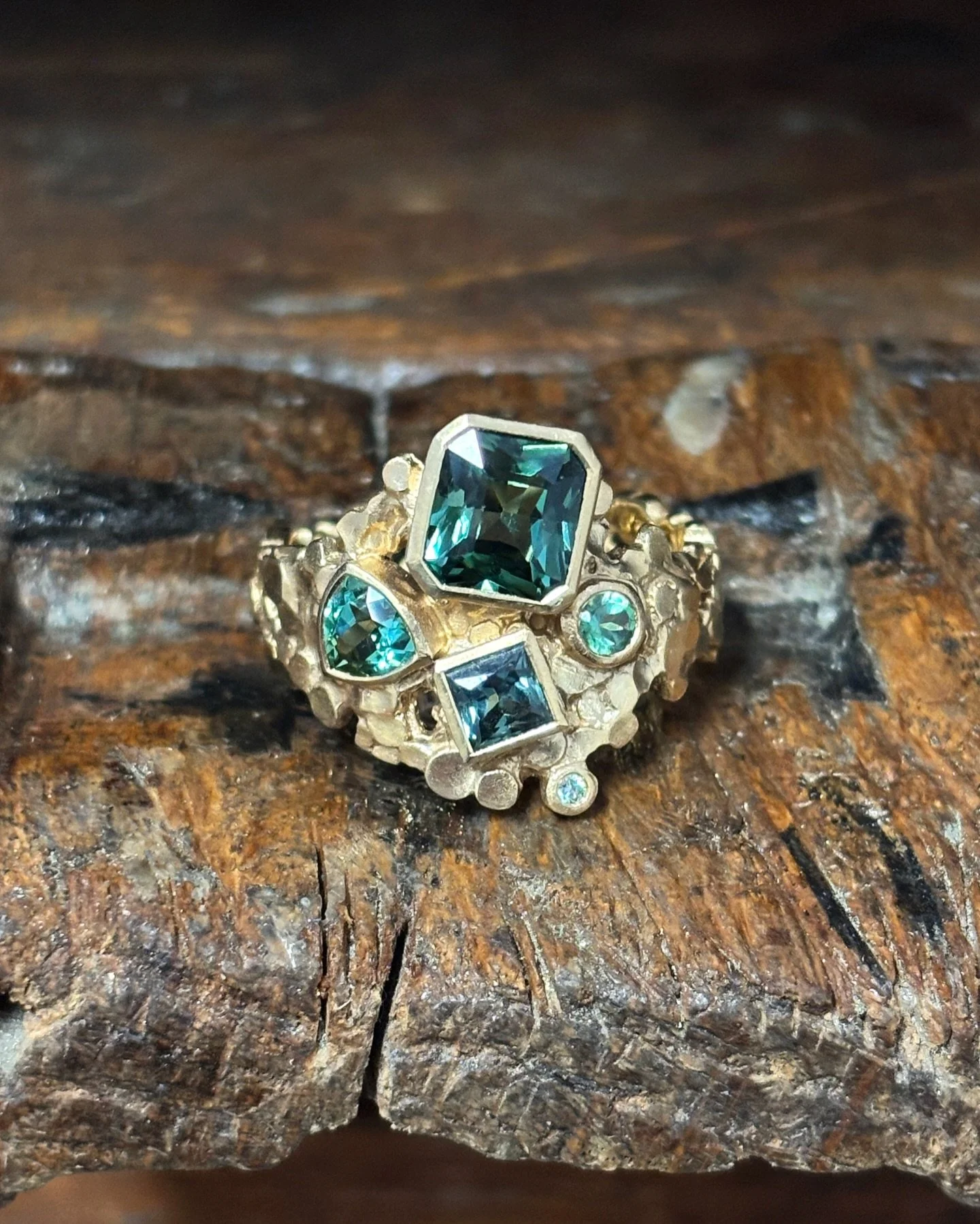 A scatter of green sapphires set into textured 18ct gold. This one grew around a stunning cushion-cut centre stone and the smaller princess, trillion and round stones found their place around it.

I always like how these multi-stone rings feel a bit 