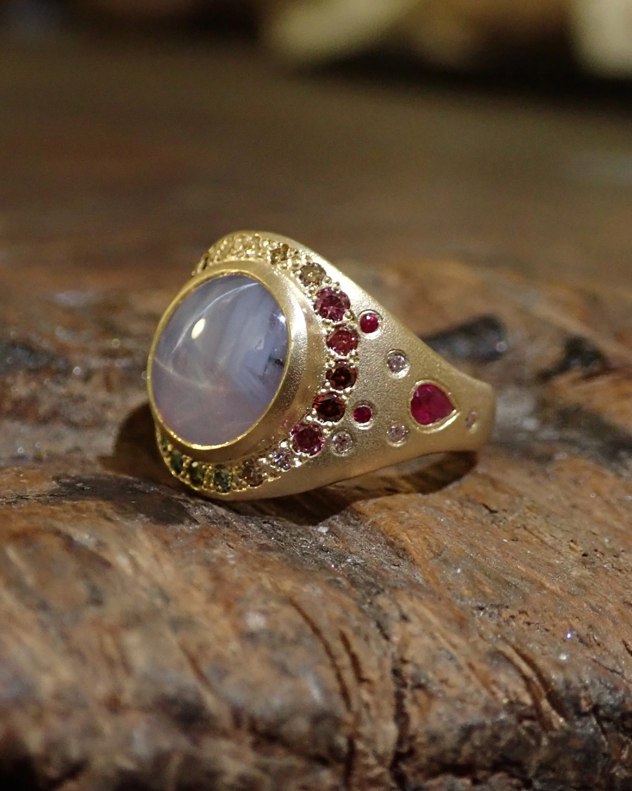 I love the soft glow of star sapphires, the way the light moves across the surface almost feels like moonlight on water. 

This one is set in rich yellow gold with rubies, sapphires, and diamonds tucked into the band, creating little flashes of colou