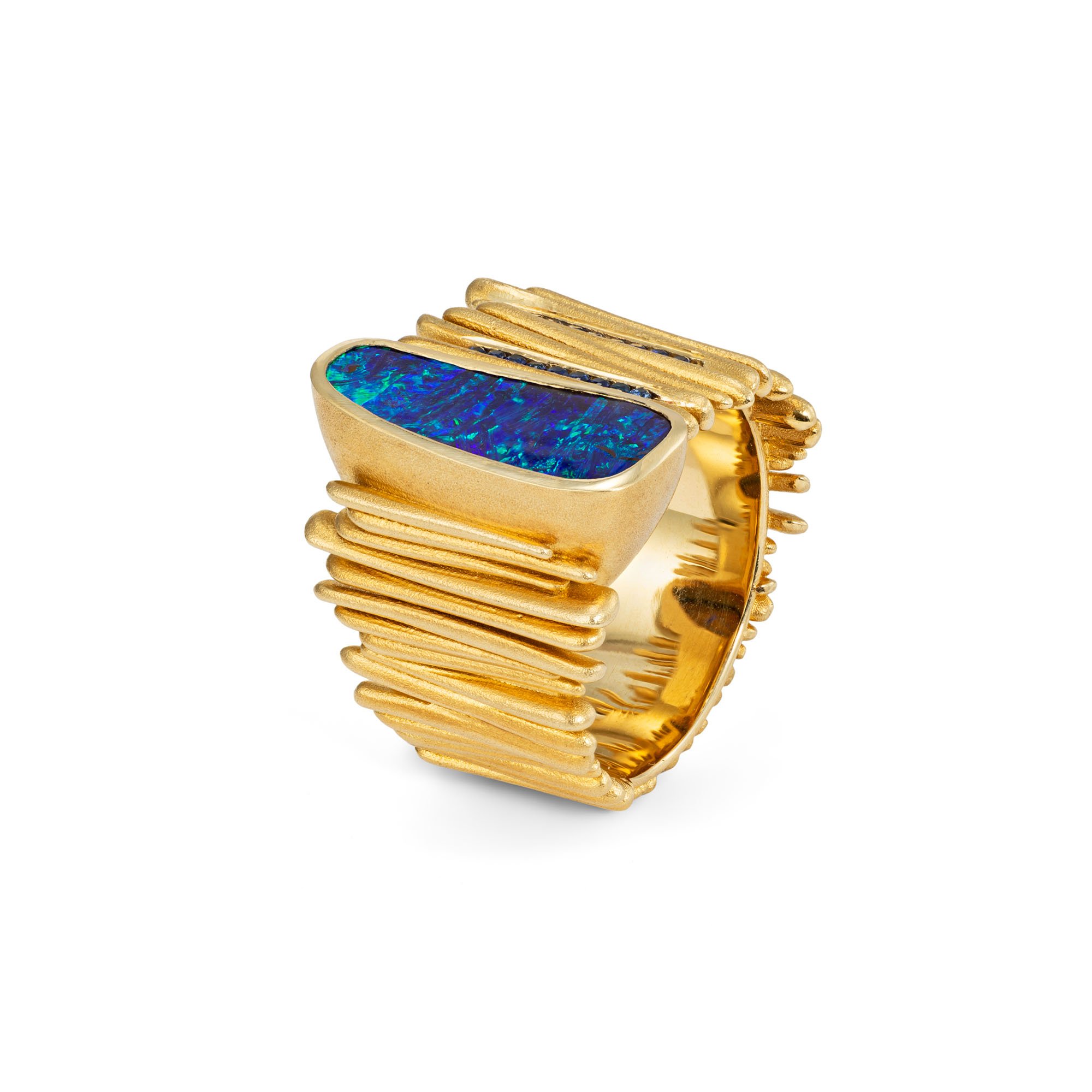 Australian opal and blue sapphire gold ring with a wide sculptural band, textured gold lines and vibrant blue-green opal.