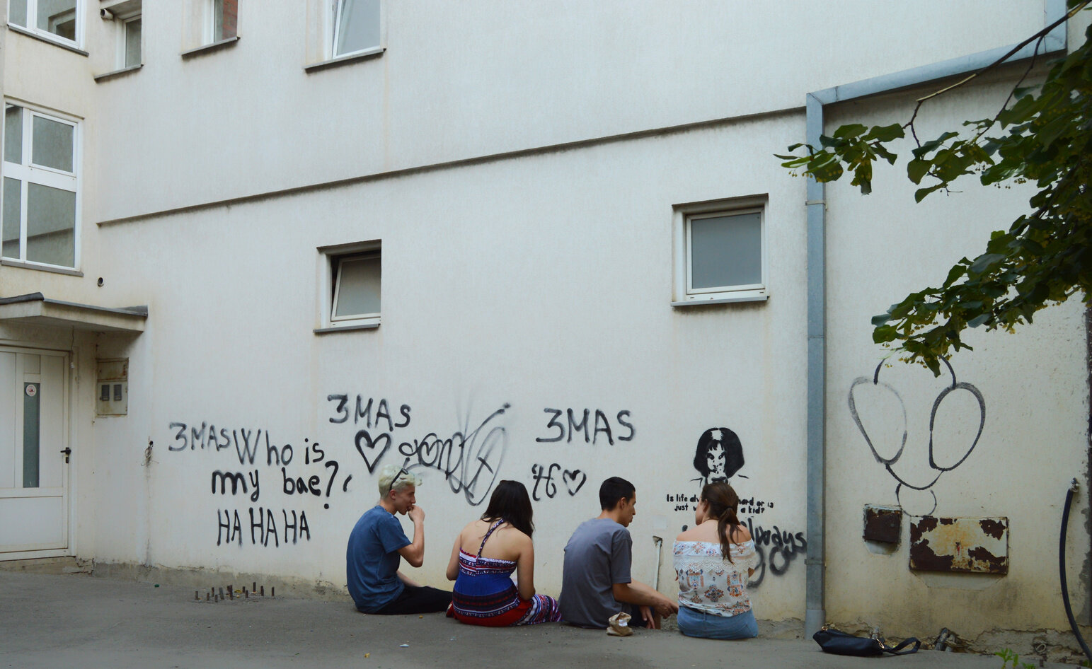 Young Kosovars sit near a graffitied wall in suburban Pristina.