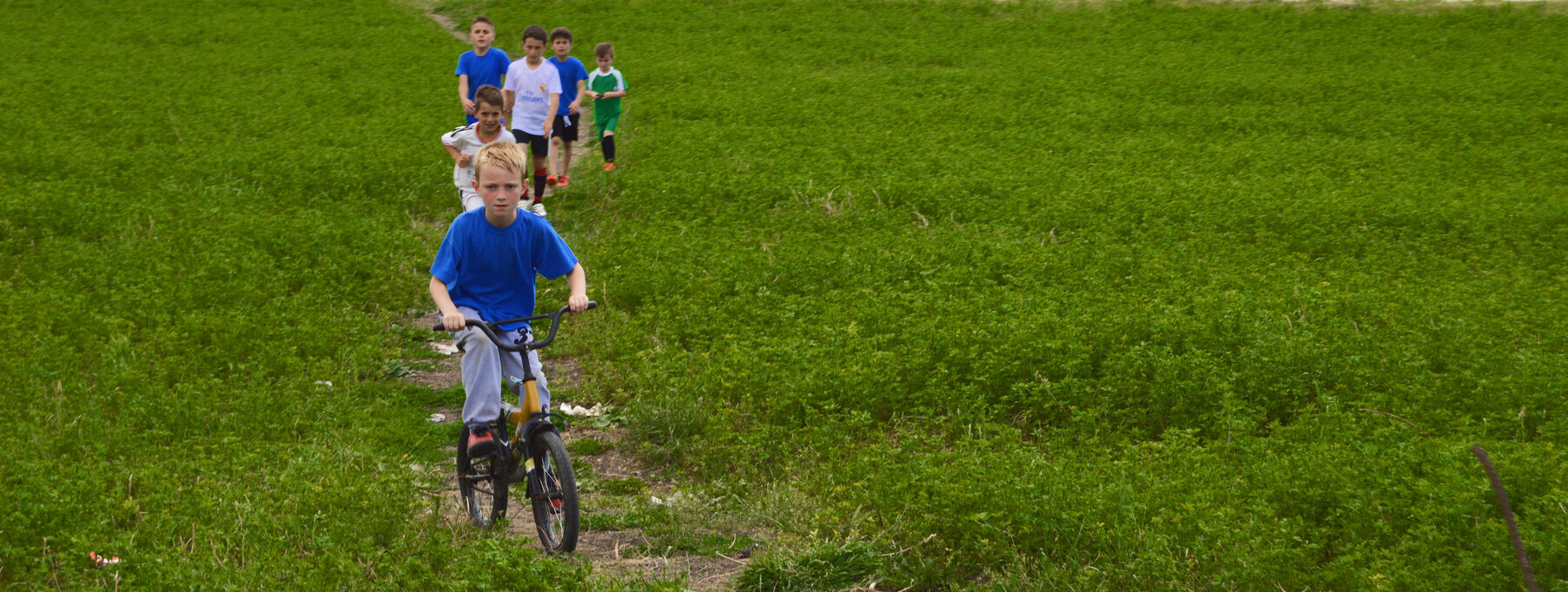Children in Skenderaj ride bikes in an open field during the summer break.