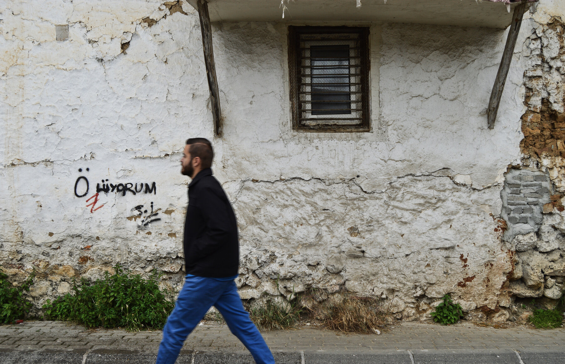 A man walks by a graffitied wall in Prizren.