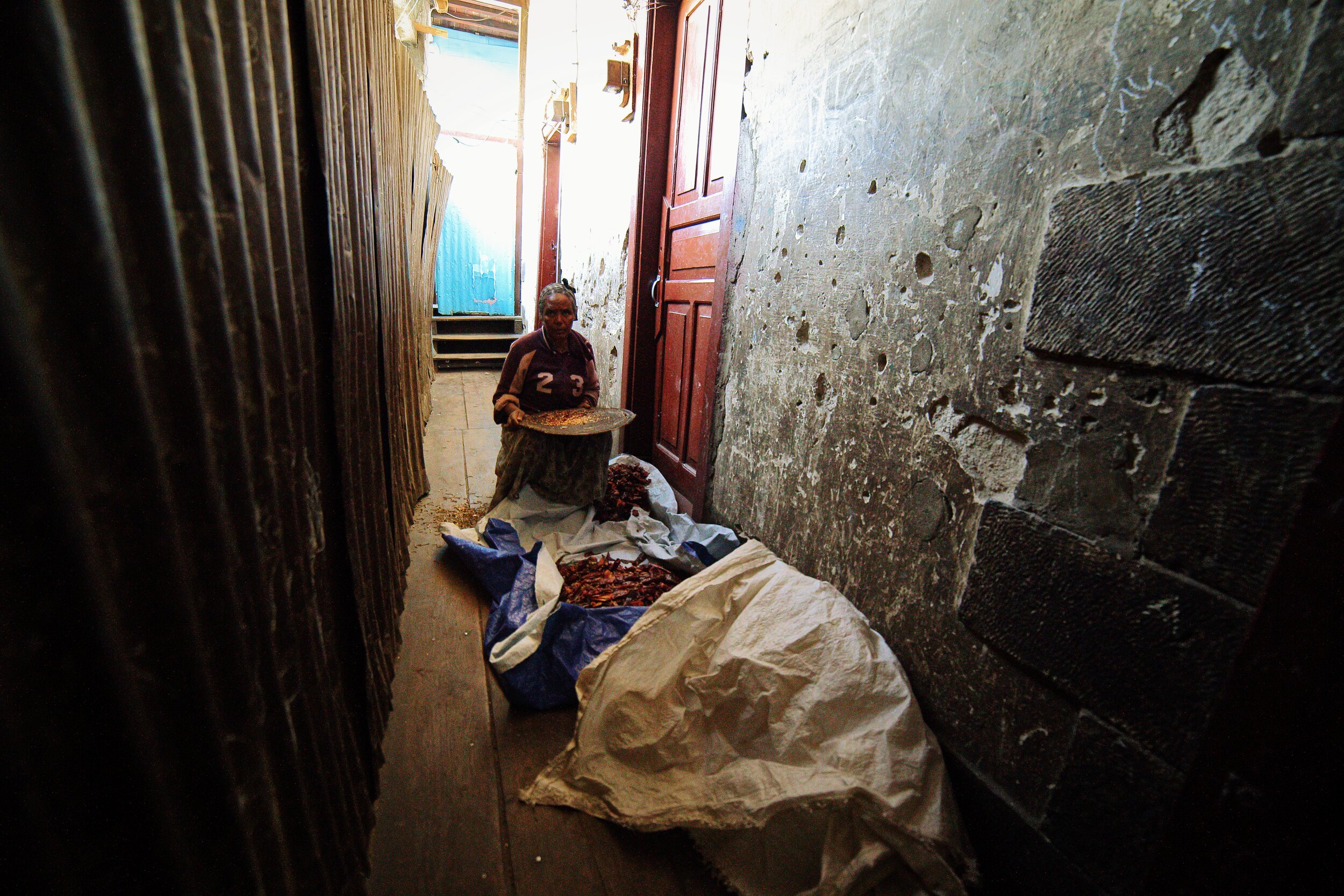  Inside the Minas Kherbekian building, traditional practices, many of them related to food preparation, remain. The woman cleans dried chilies in the corridor in from of her apartment which are used in many Ethiopian dishes. 