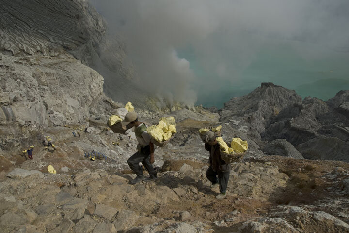  Miners carry heavy loads of sulfur weighing over 70 kilograms up the vertical path from the green volcanic lake below. 