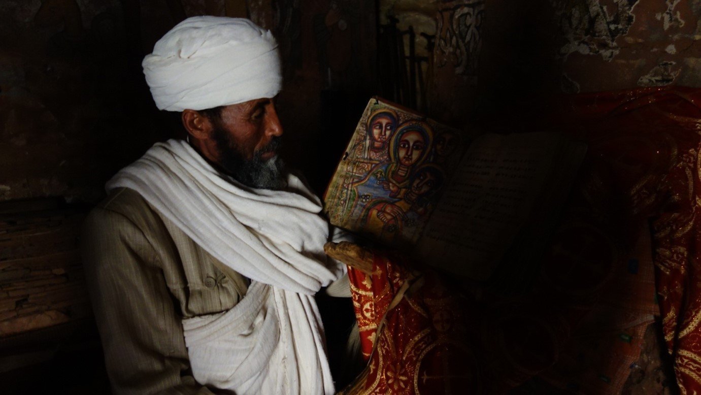  A priest displays a medieval illuminated manuscript in the rock-hewn church Abuna Yemata Guh. 