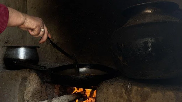   Photo 3:  A woman prepares a meal over a woodfire inside her home in rural Pakistan. Domestic spaces such as these reflect the often unseen labor of women, whose daily contributions sustain families amid prolonged displacement. 