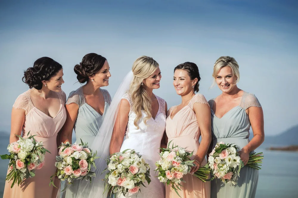 Bride laughing with her bridesmaids by the water