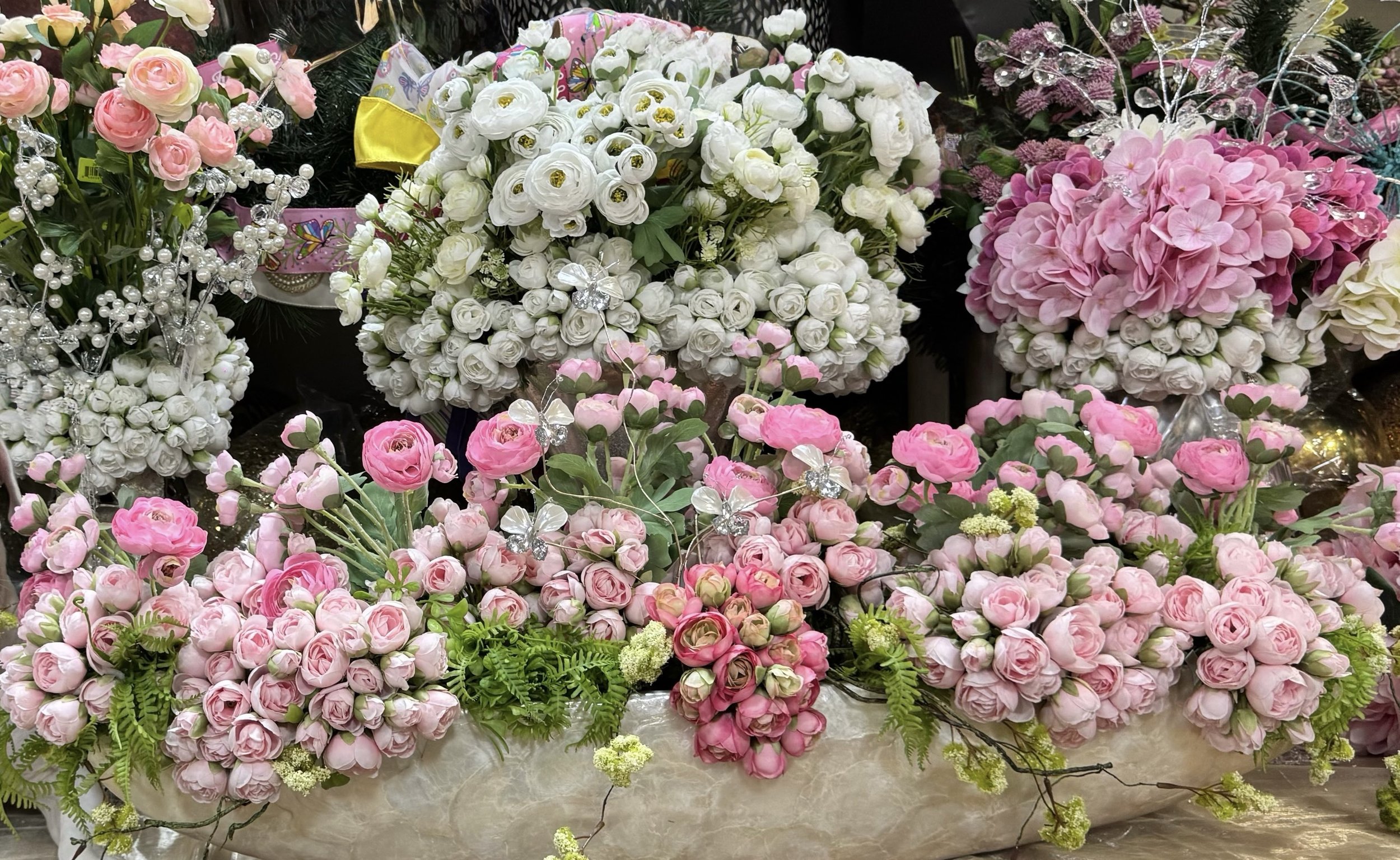 Blush and white silk roses and ranunculus displayed by color in the Arcadia Houston showroom