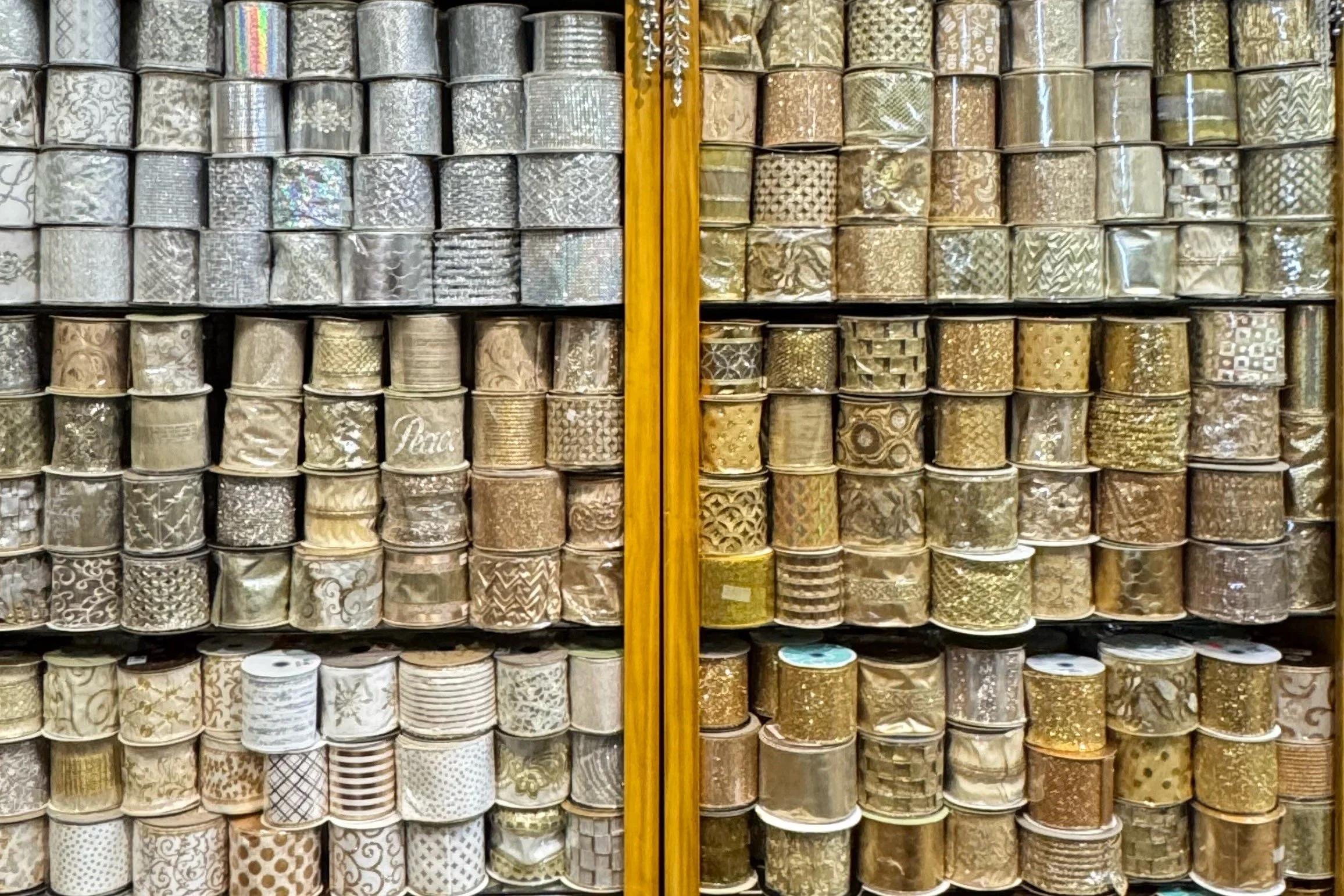 Floor-to-ceiling display of gold and silver wired ribbon organized by color at Arcadia’s Houston showroom