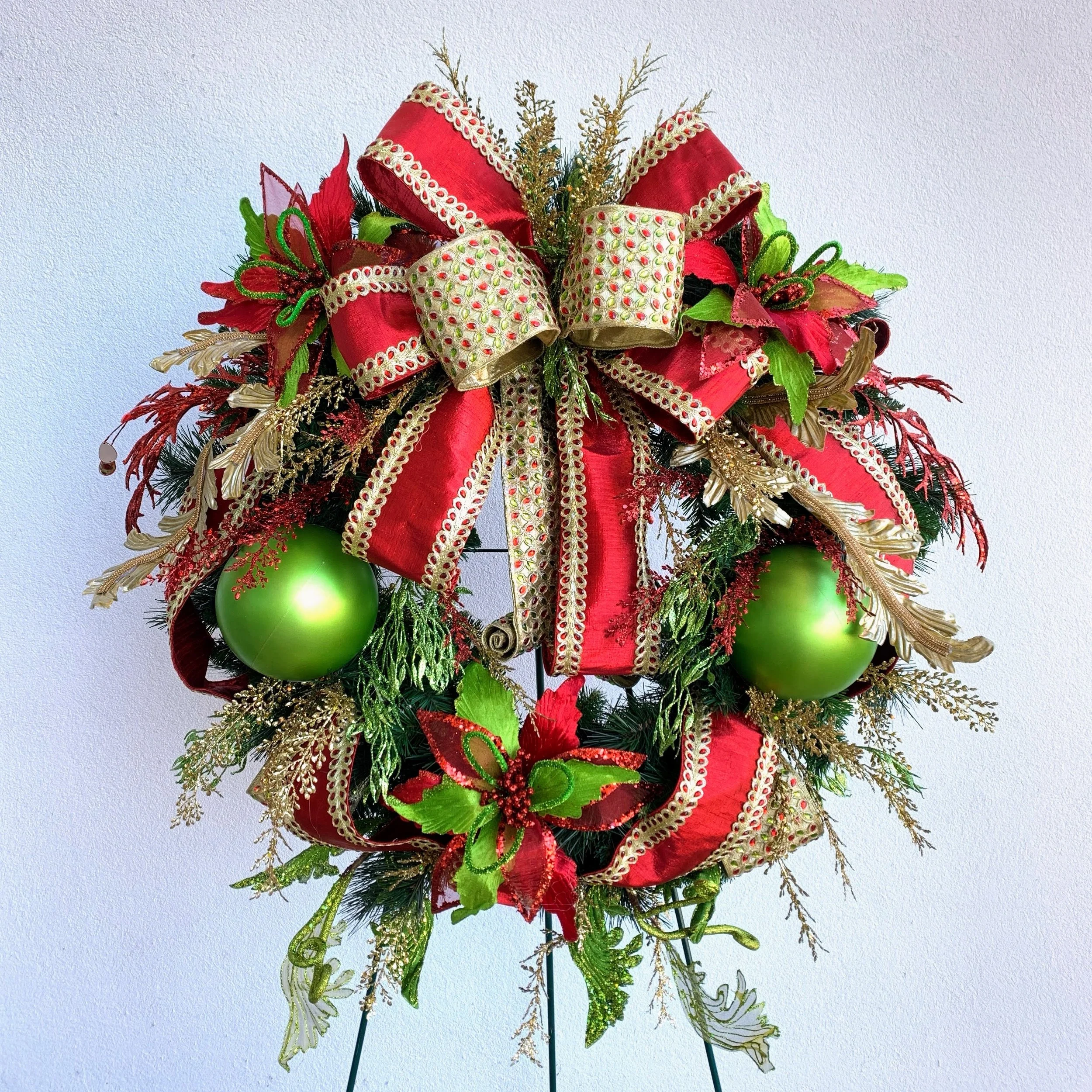 Hand-finished Christmas wreath in red, green, and gold with layered ribbon