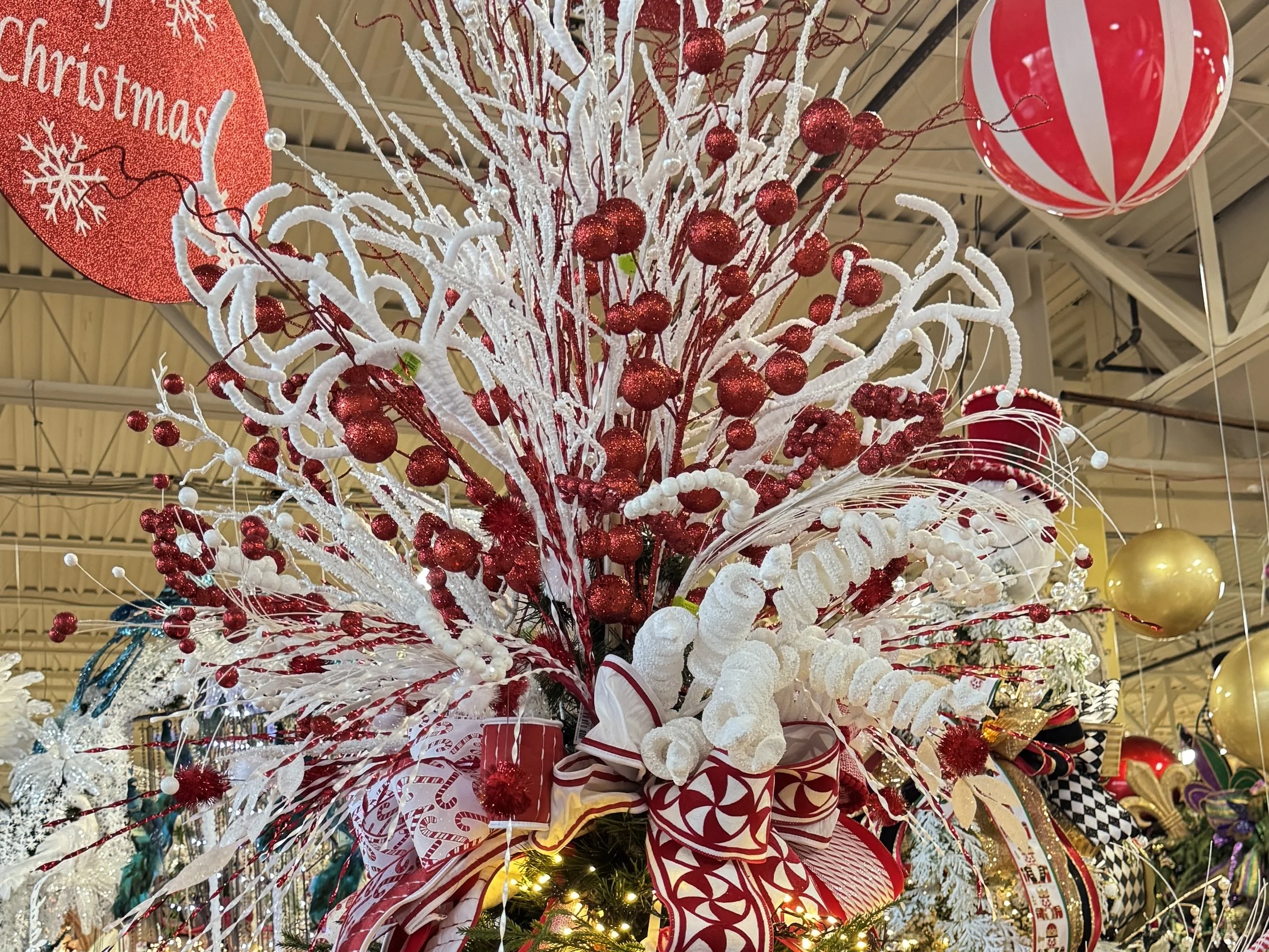 Close-up of a Christmas tree topper built from red glitter berry sprays and white curly picks