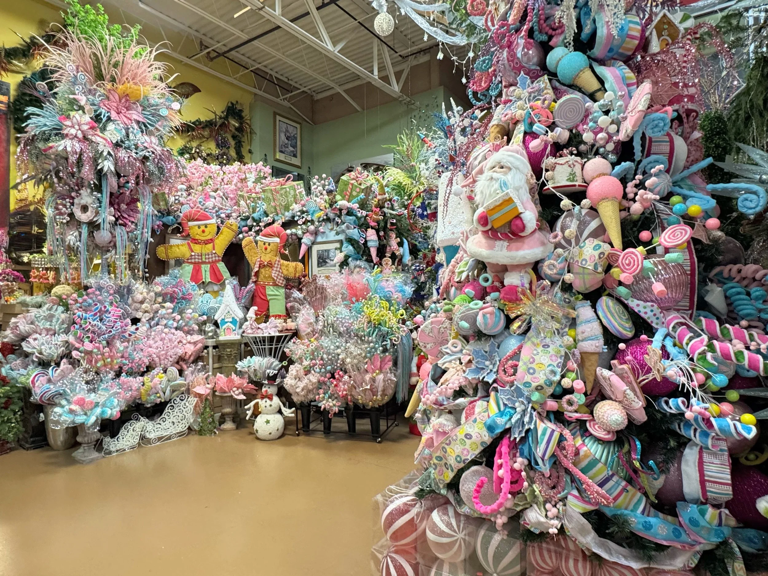Pastel candy and gingerbread themed Christmas trees with lollipops, ice cream ornaments, and gingerbread figures in Arcadia’s Houston showroom