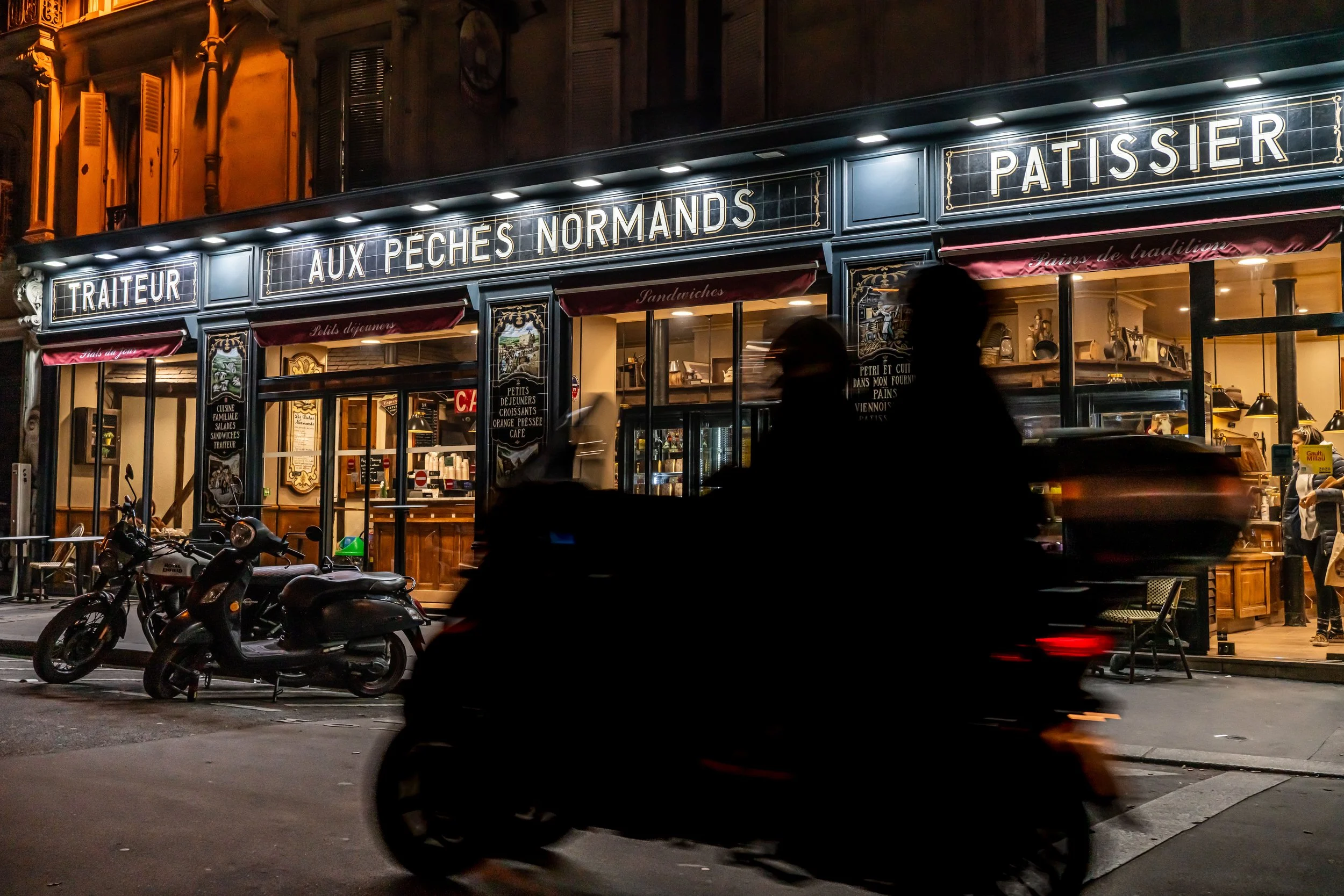 Paris - Neon glows embrace the patisserie’s warmth, while fleeting silhouettes whisper secrets across midnight streets.