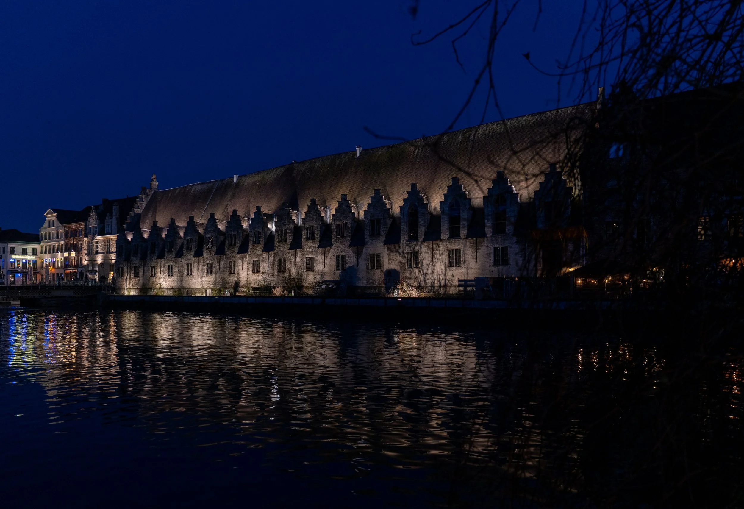 Gent: Shadows and lights carve the waterfront, where history leans quietly into the water.