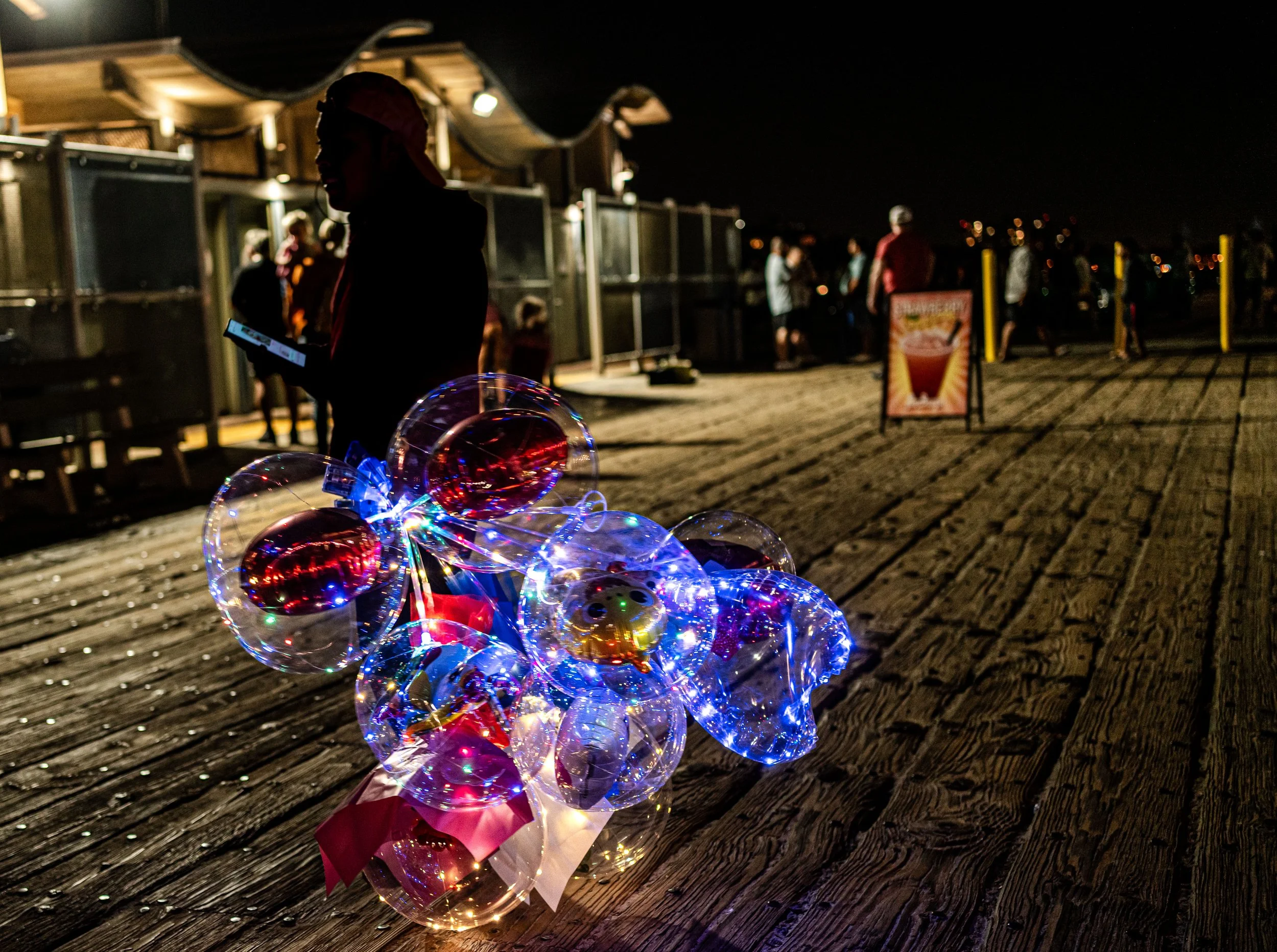 Santa Monica - In the night’s hush, balloons glow like captured stars, carrying fragile dreams across the pier.