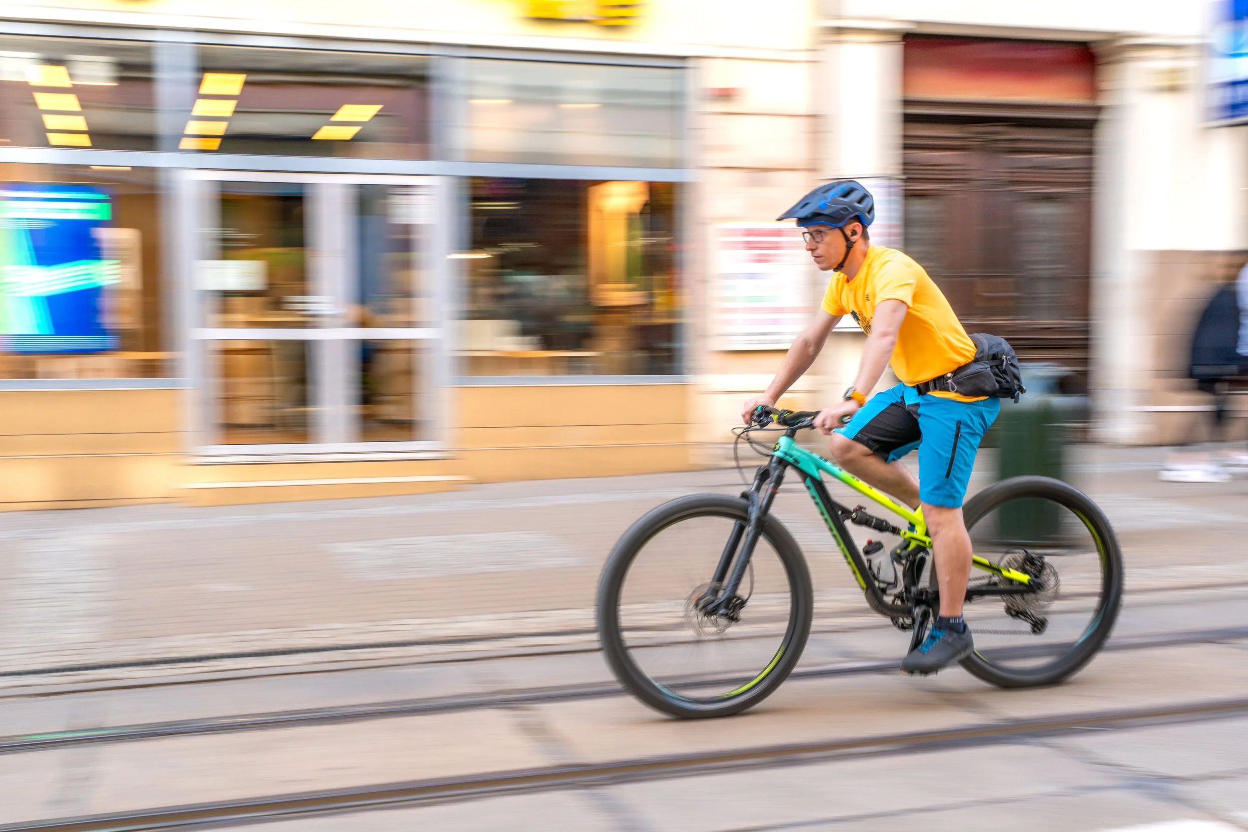 Bydgoszcz - Golden shirt, swift wheels, city blurs—he rides through fleeting moments, carving silence from rushing streets.