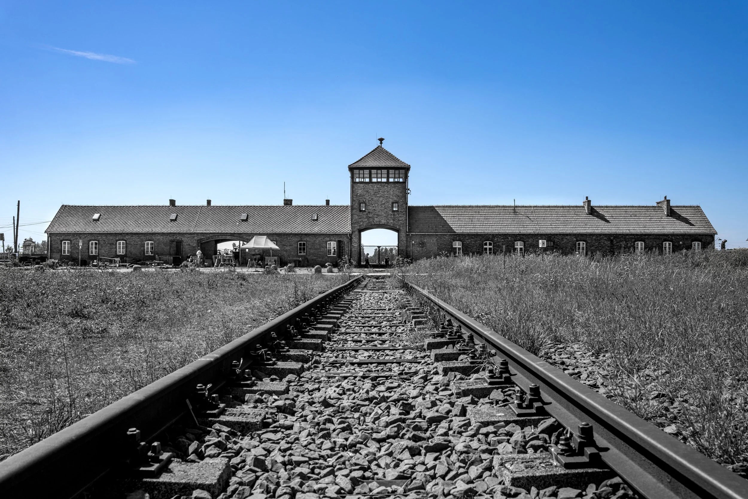 On these tracks millions were taken to their fate — the blue sky above whispers a hope for a different future.