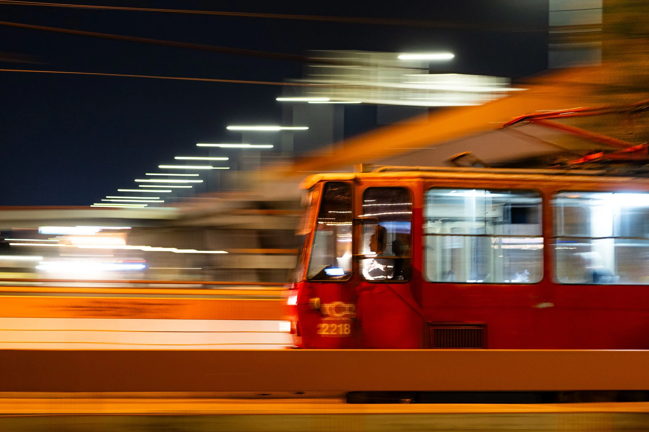 Belgrade - Red tram slicing night, lights blur, a fleeting silhouette rides the city’s pulse.