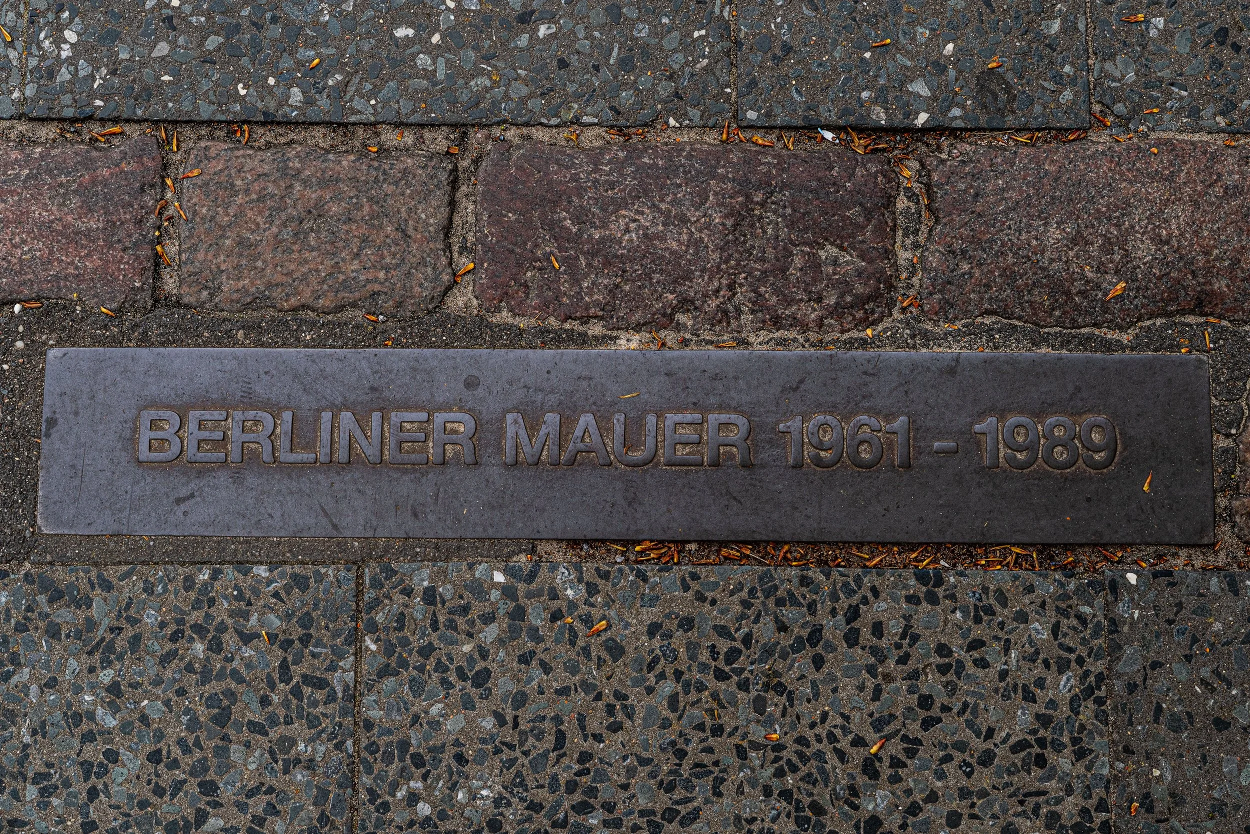 Berlin – Stones trace a vanished wall, dividing memory and freedom, footsteps echo where history once fractured.
