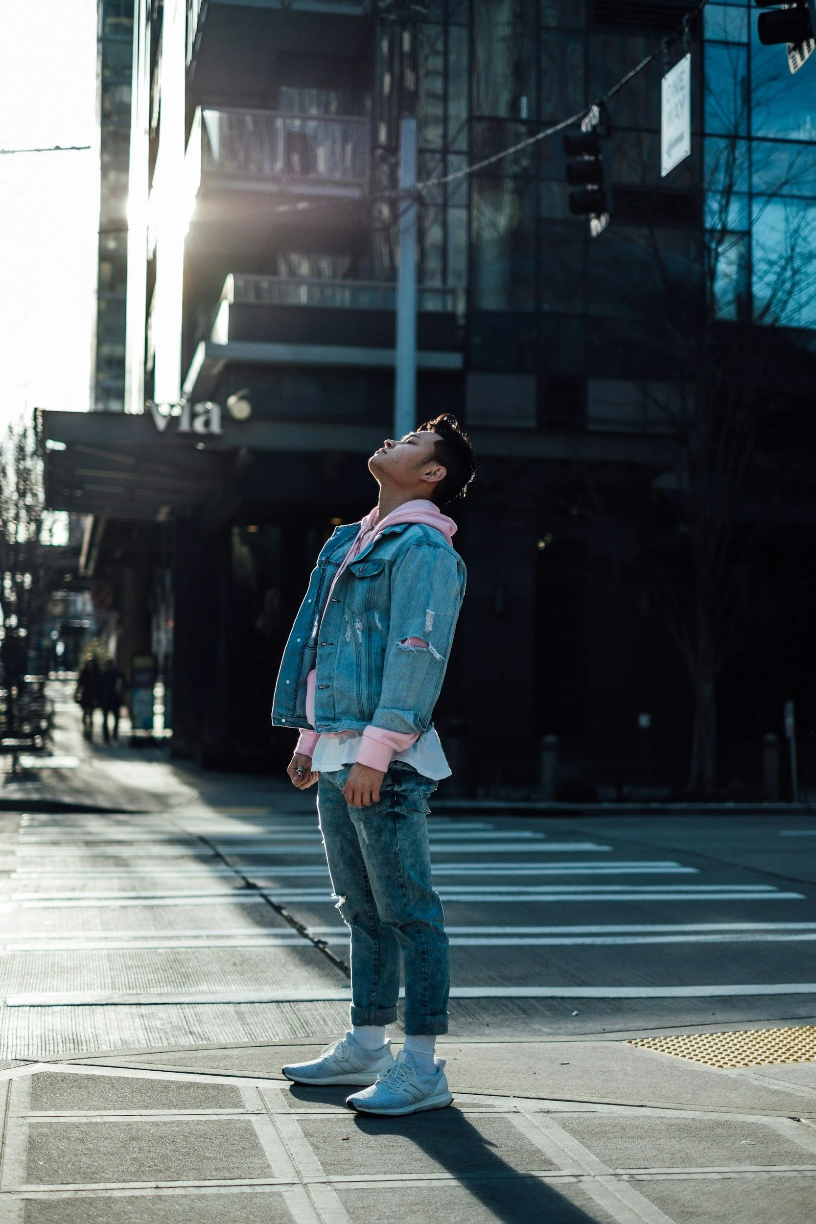 male standing near crosswalk staring up with eyes closed feeling the sun on his skin
