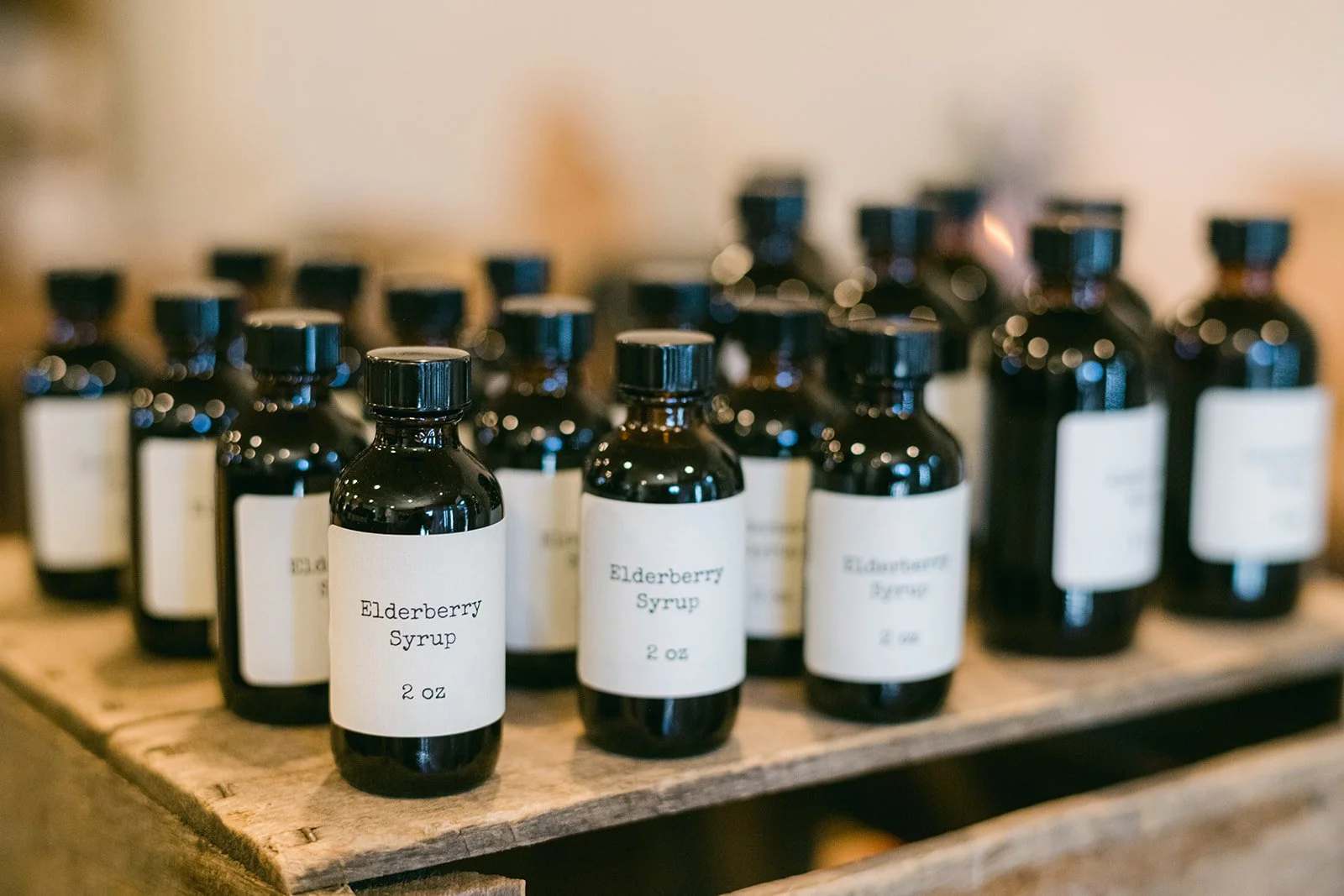 Dark glass bottles of elderberry syrup lined up on a wooden crate