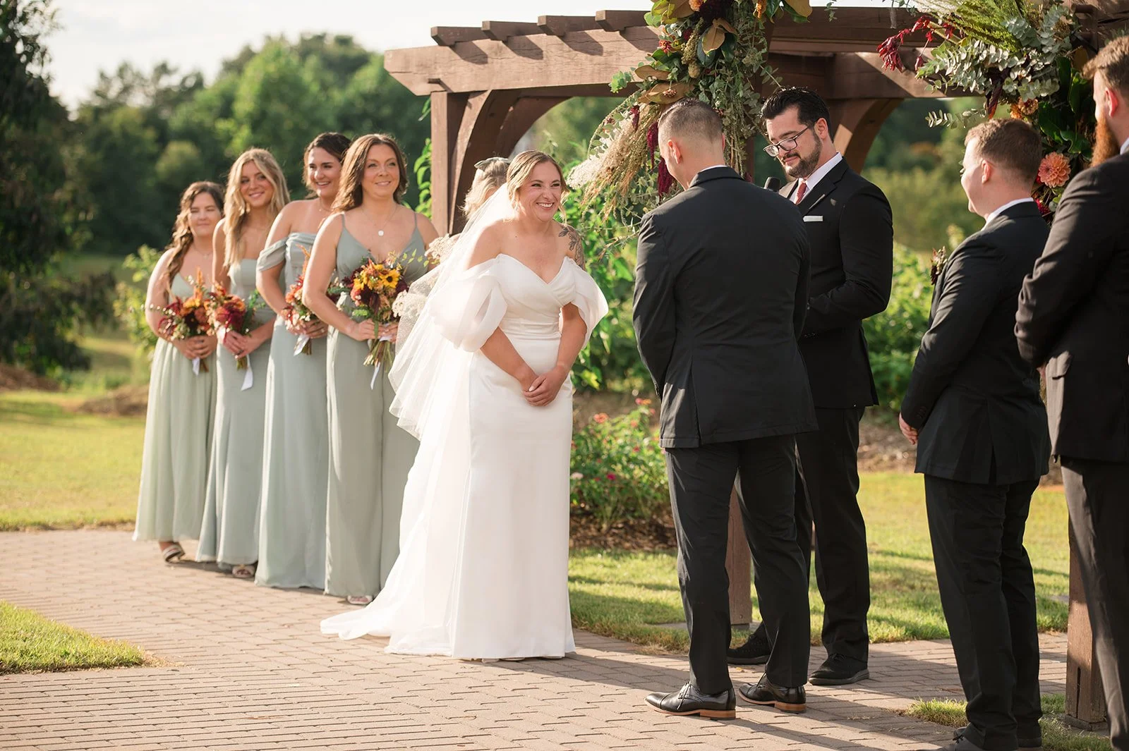 Wedding ceremony outdoors beneath decorated wooden archway