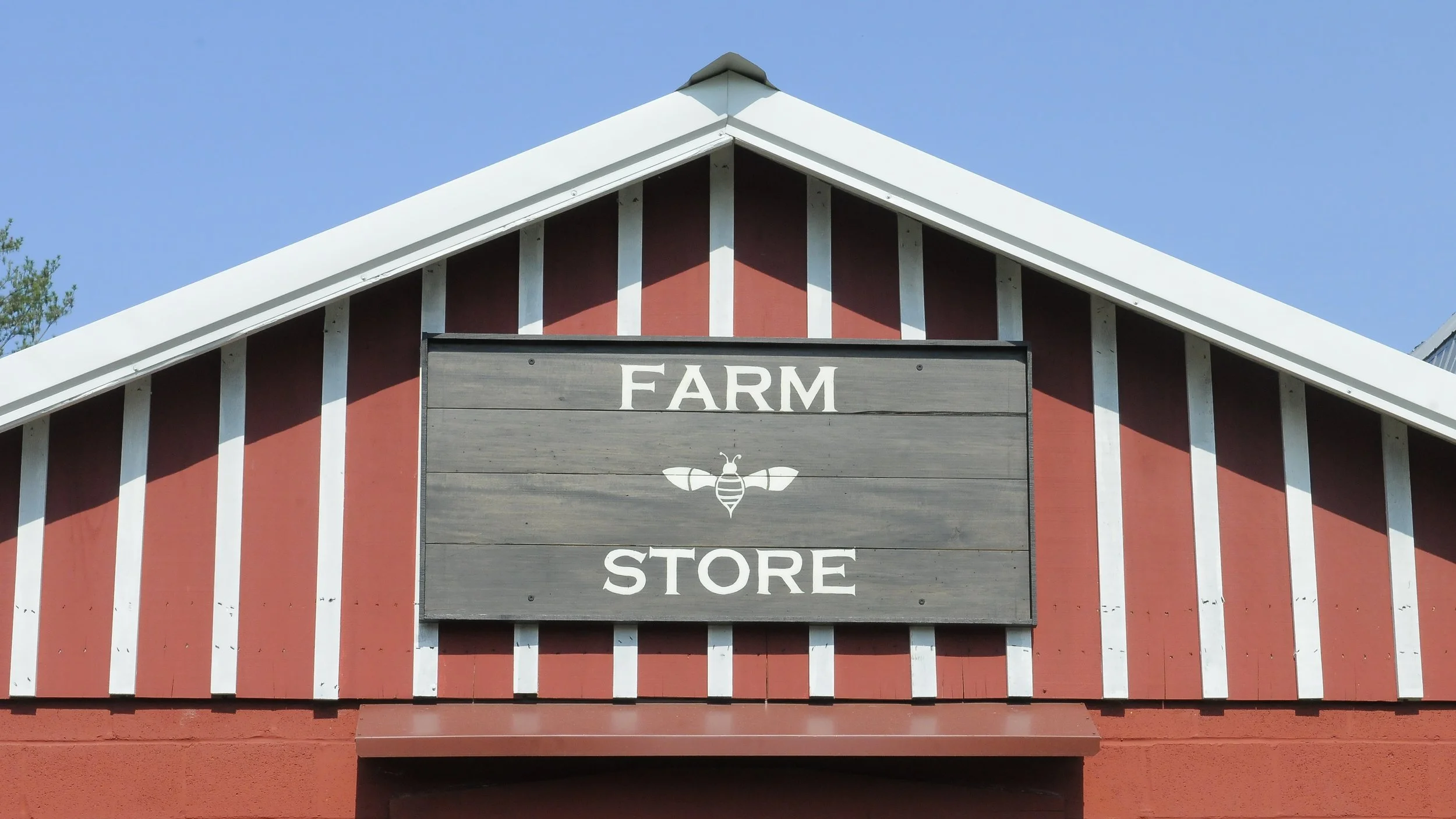 Roofline of a red building with a sign that says Farm Store against a blue sky