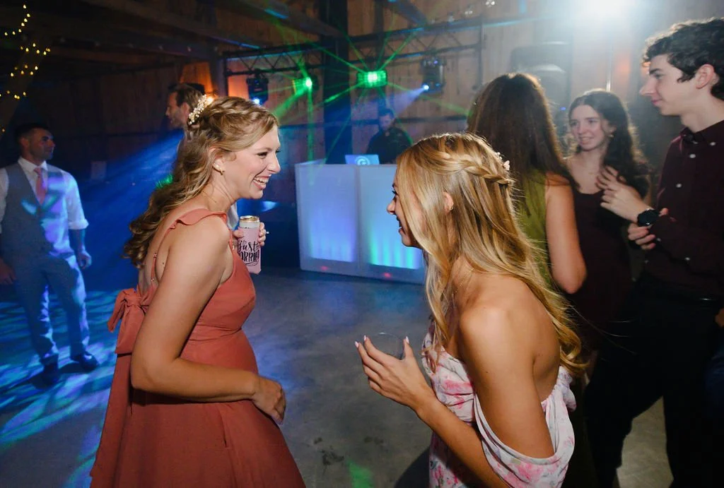 Two women laughing in a wooden space with blue and green lights