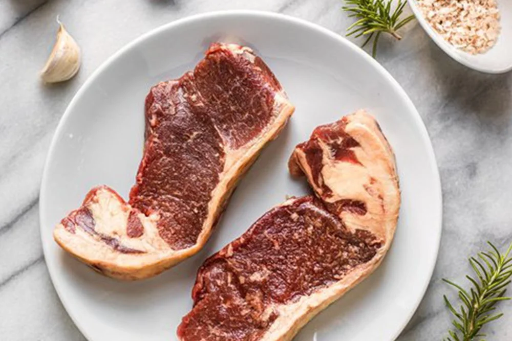 a plated view of two grass-fed new york strip steaks