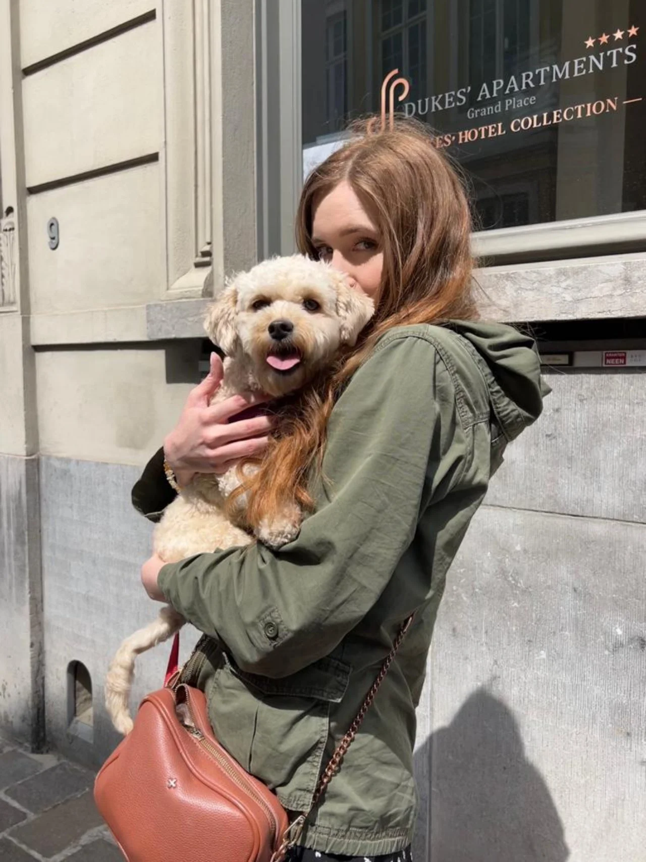 Girl on street hugging cream-coloured poodle