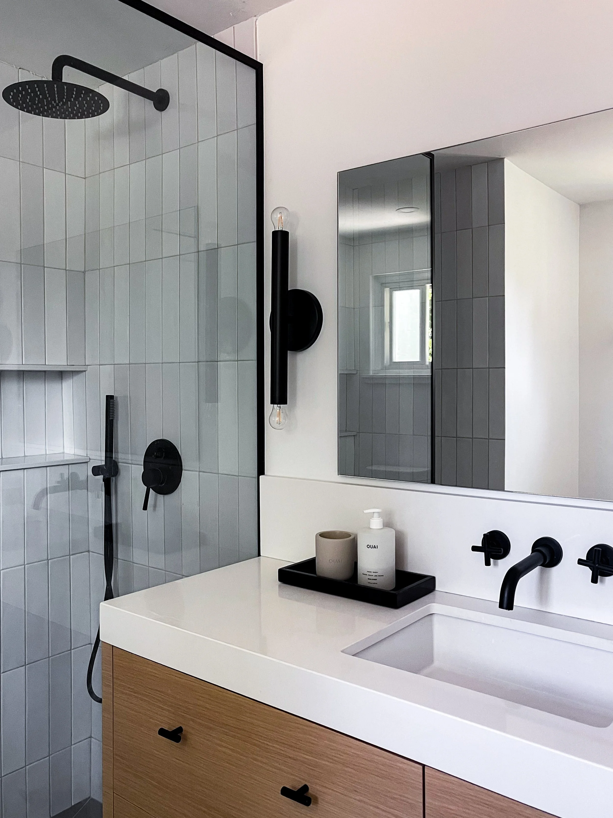White subway tile shower in Vaughan bathroom renovation with black handheld wand, recessed niche shelf, and modern matte fixtures