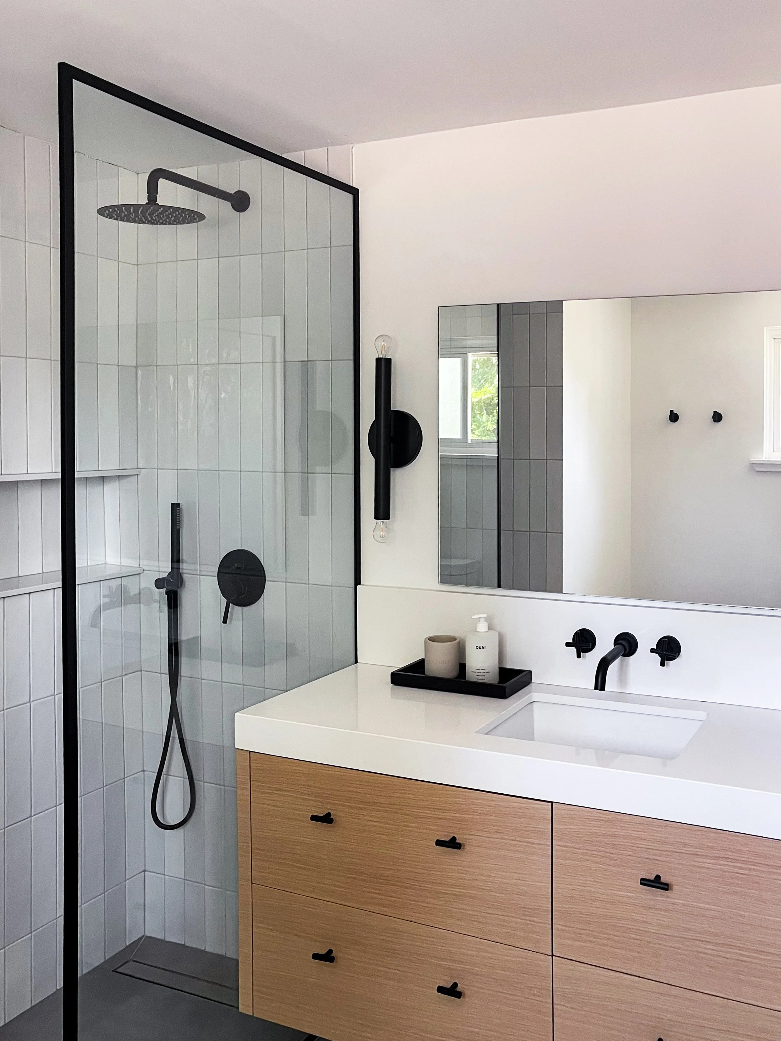 Complete Vaughan bathroom transformation with white subway tile walls, frameless glass shower, floating wood vanity, and round mirror