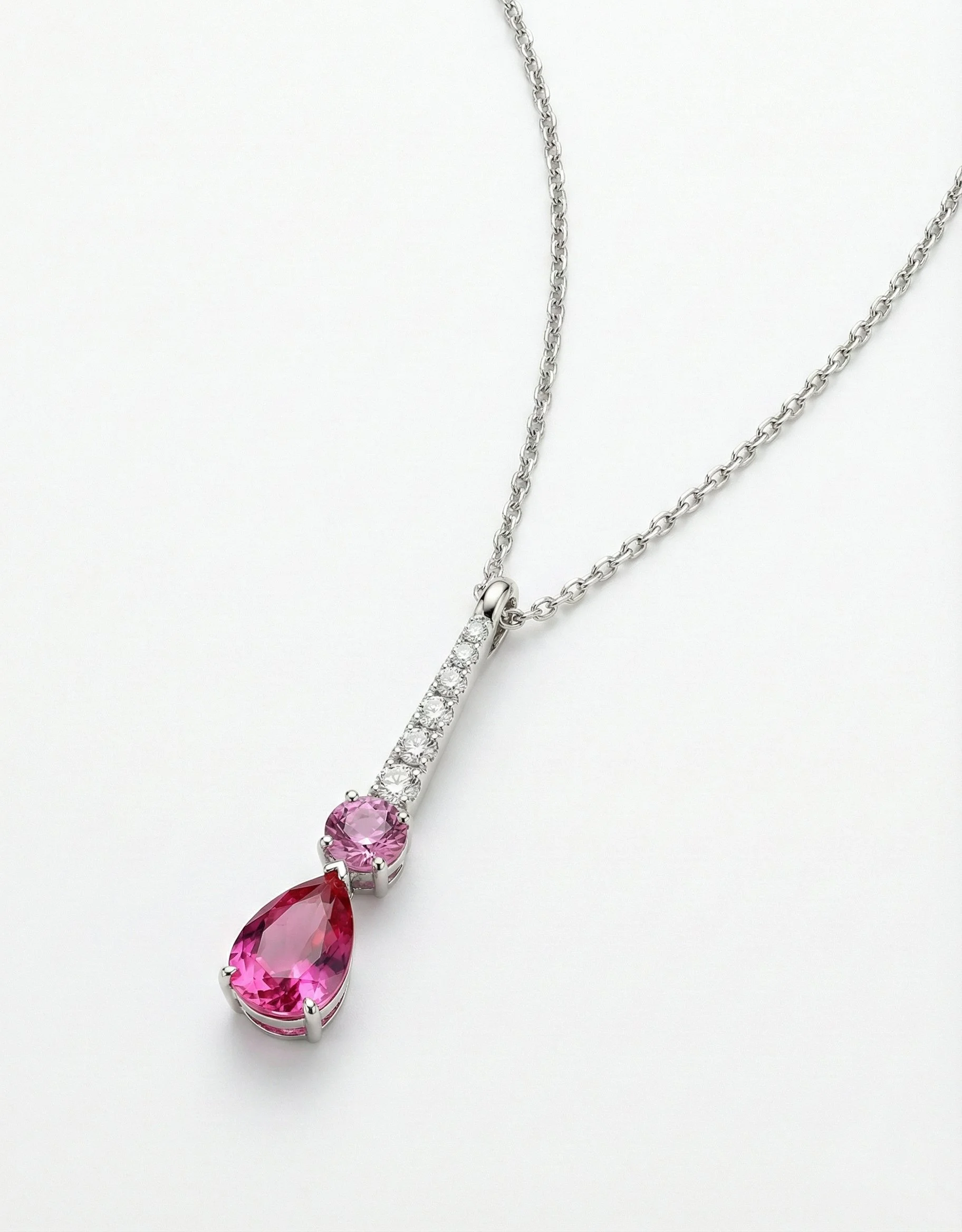 Silver necklace with pink gemstone and smaller pink gemstones and clear stones on a white background.