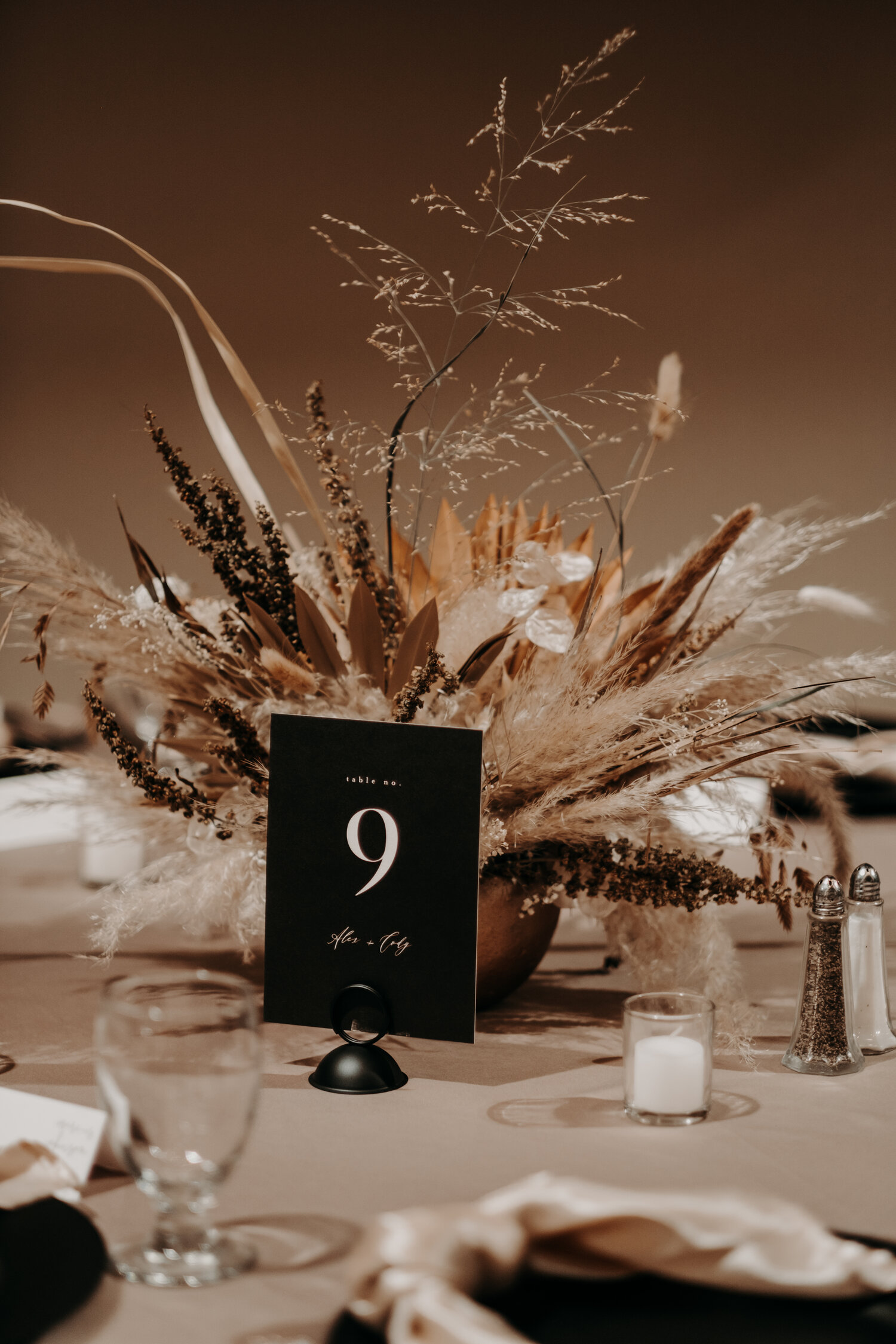 Photo by Katy Elaine Photography. Our bride Alex chose tablescapes that were easy to assemble because of their simplicity, but touches like satin napkins, matte black chargers, matte black signage, and Free State Flora dried centerpieces made a huge statement!