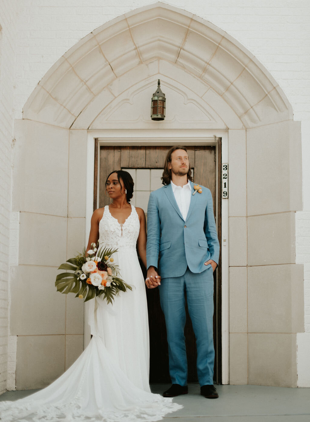 Photo of bride and groom holding hands in front of a door taken by Courtney Mitchell Photo. 