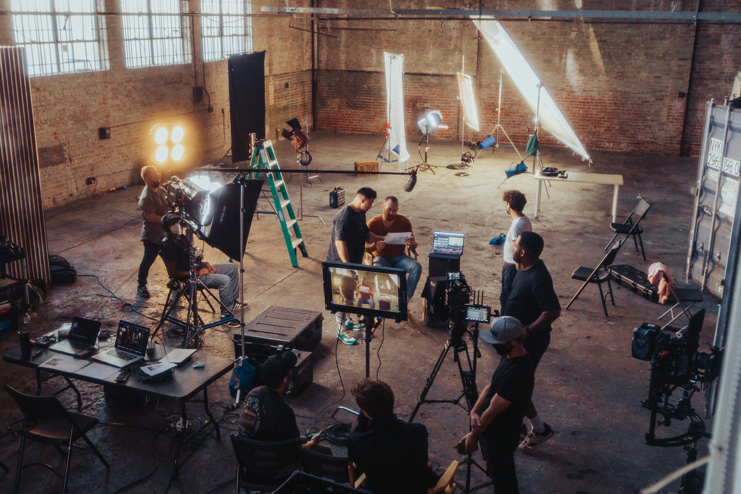 Film crew arranging cameras and lighting for a commercial production in a large studio