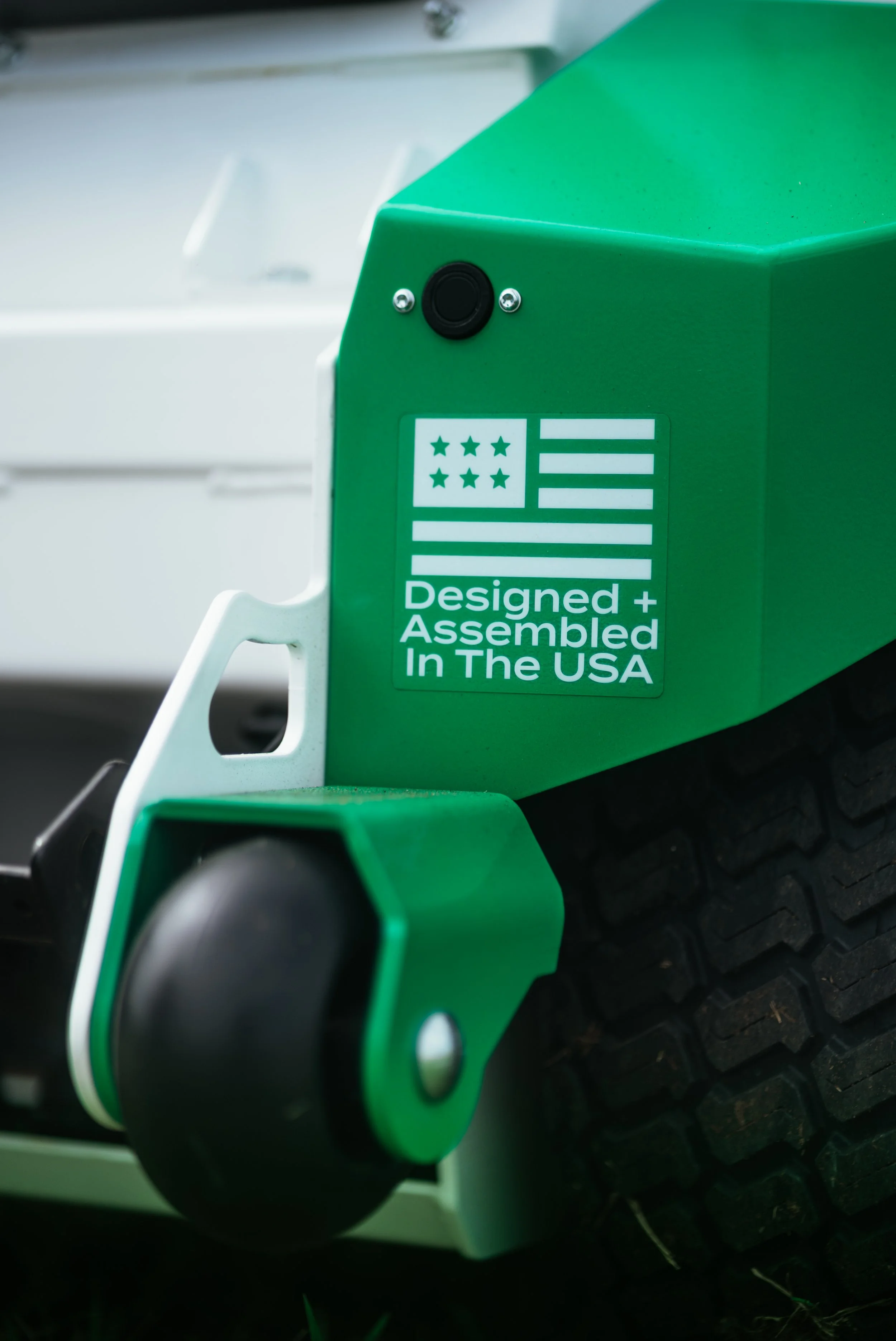 Close-up of a green industrial machine part with a logo and text that reads 'Designed + Assembled In The USA'.