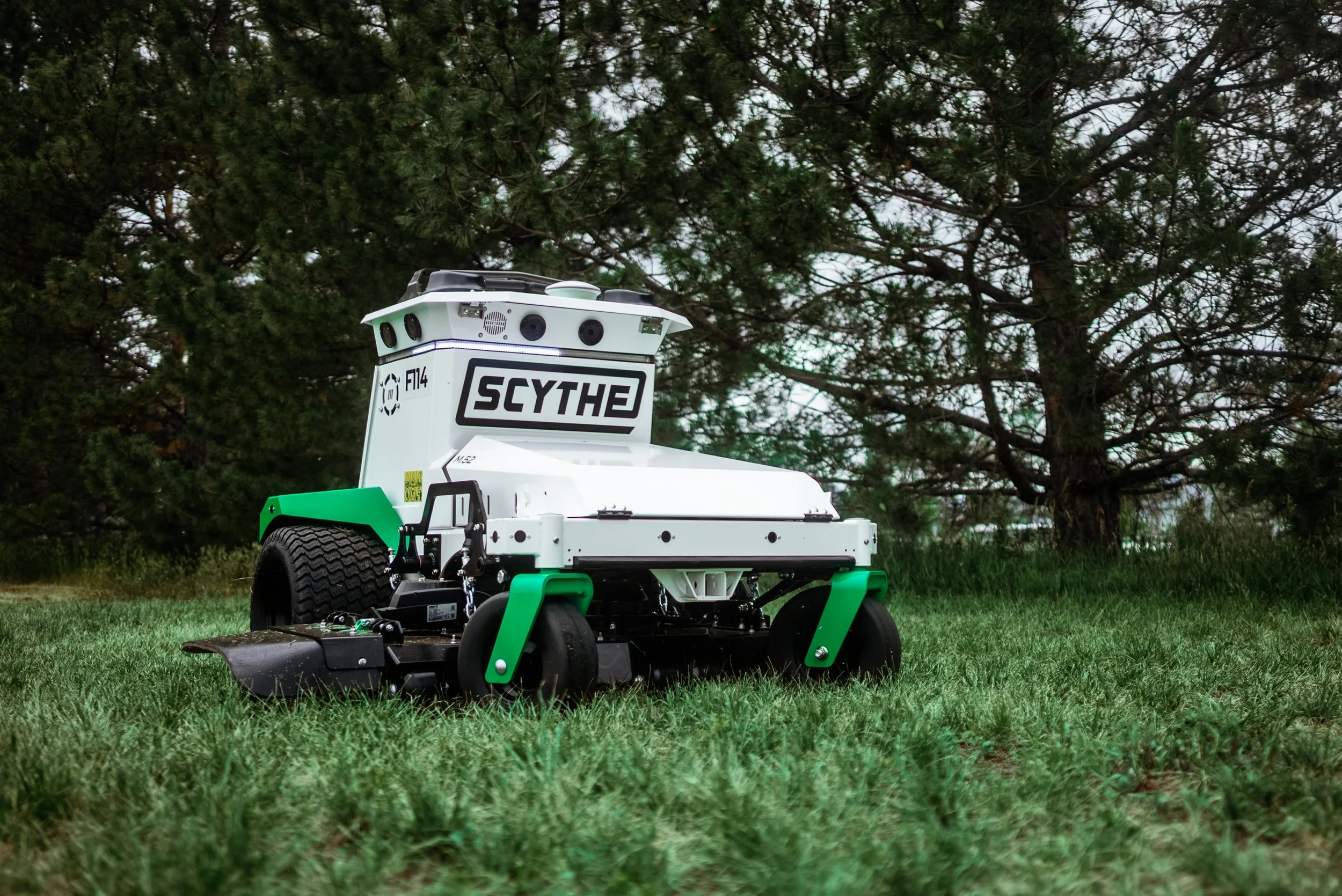 Scythe autonomous mower on grass beneath trees in the robotics campaign