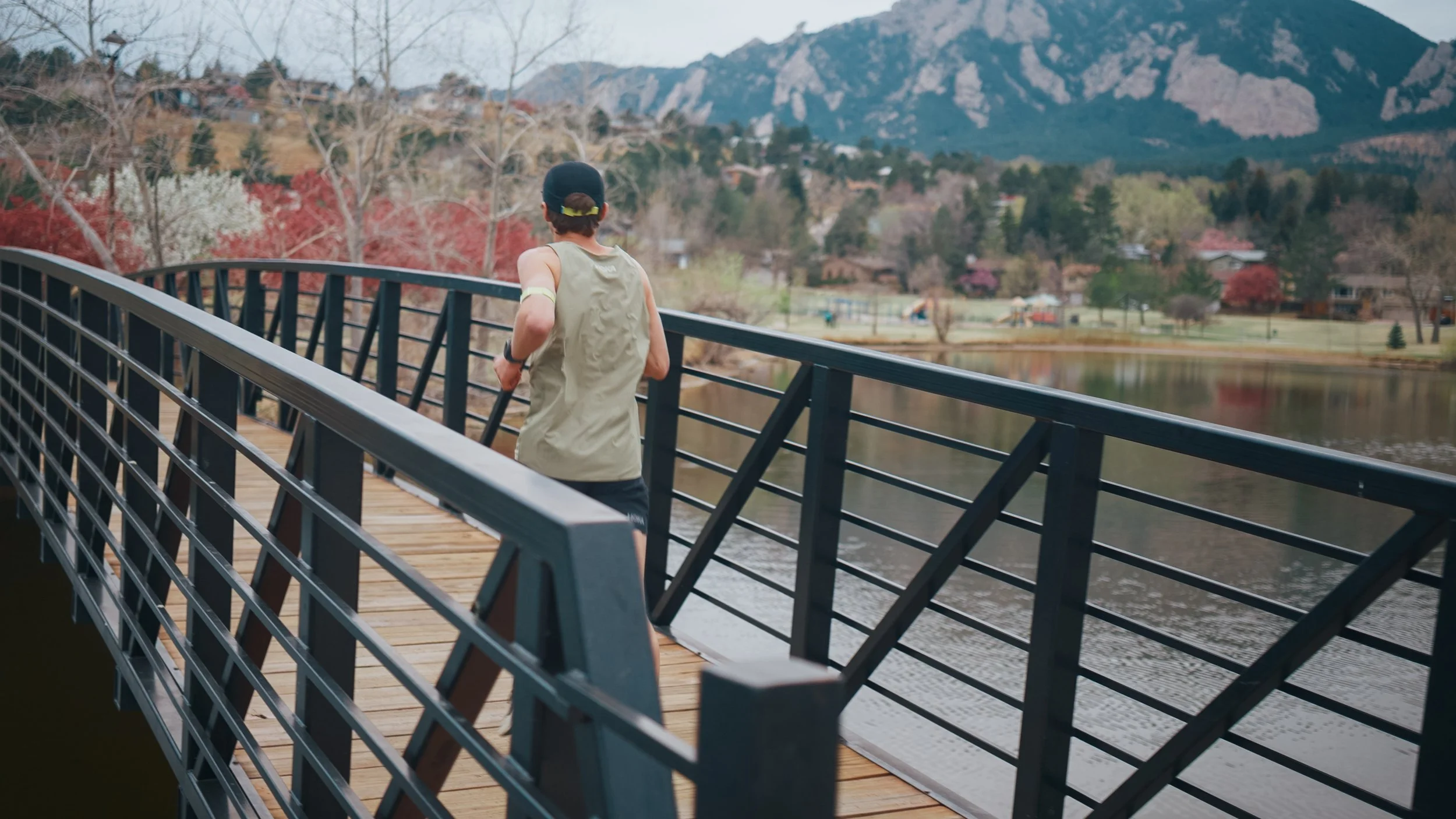 Hans Troyer running across a bridge with Boulder foothills beyond