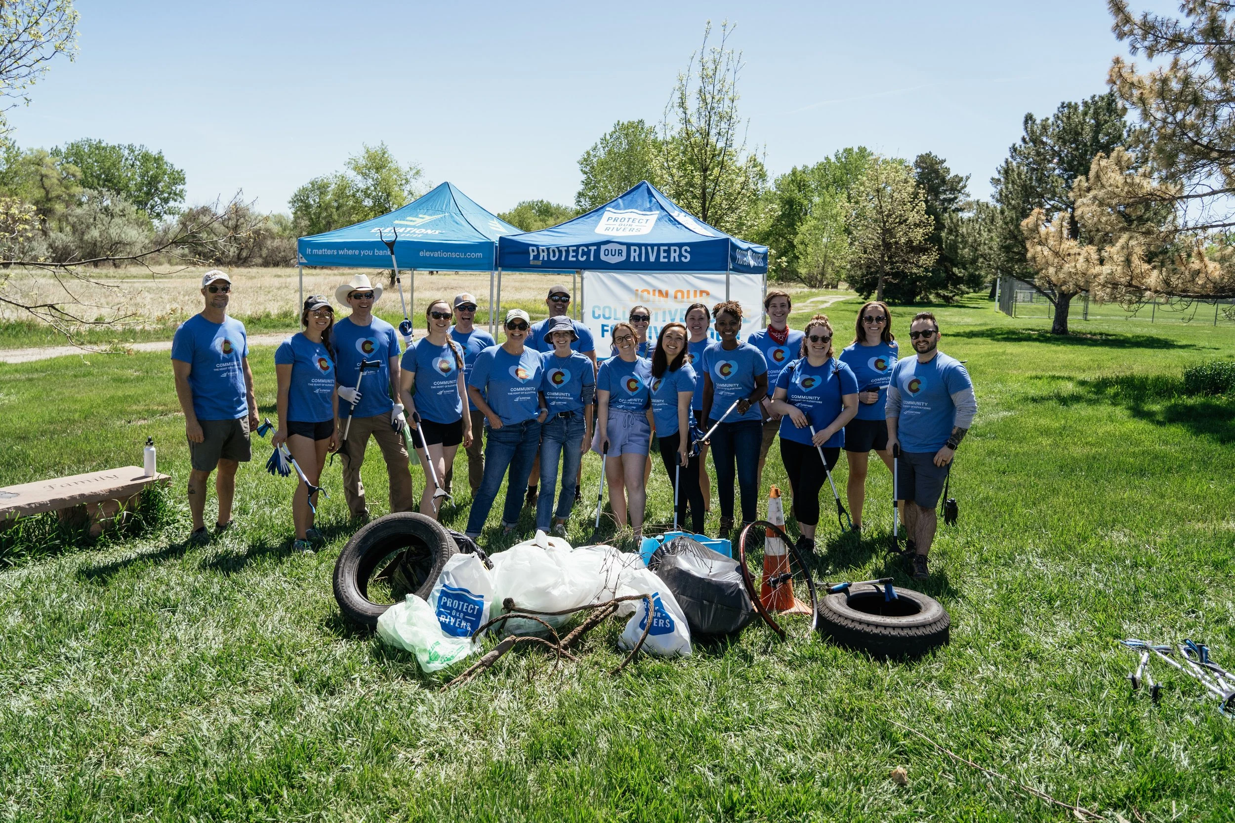 Elevations Credit Union volunteers gathered with cleanup supplies beside the river