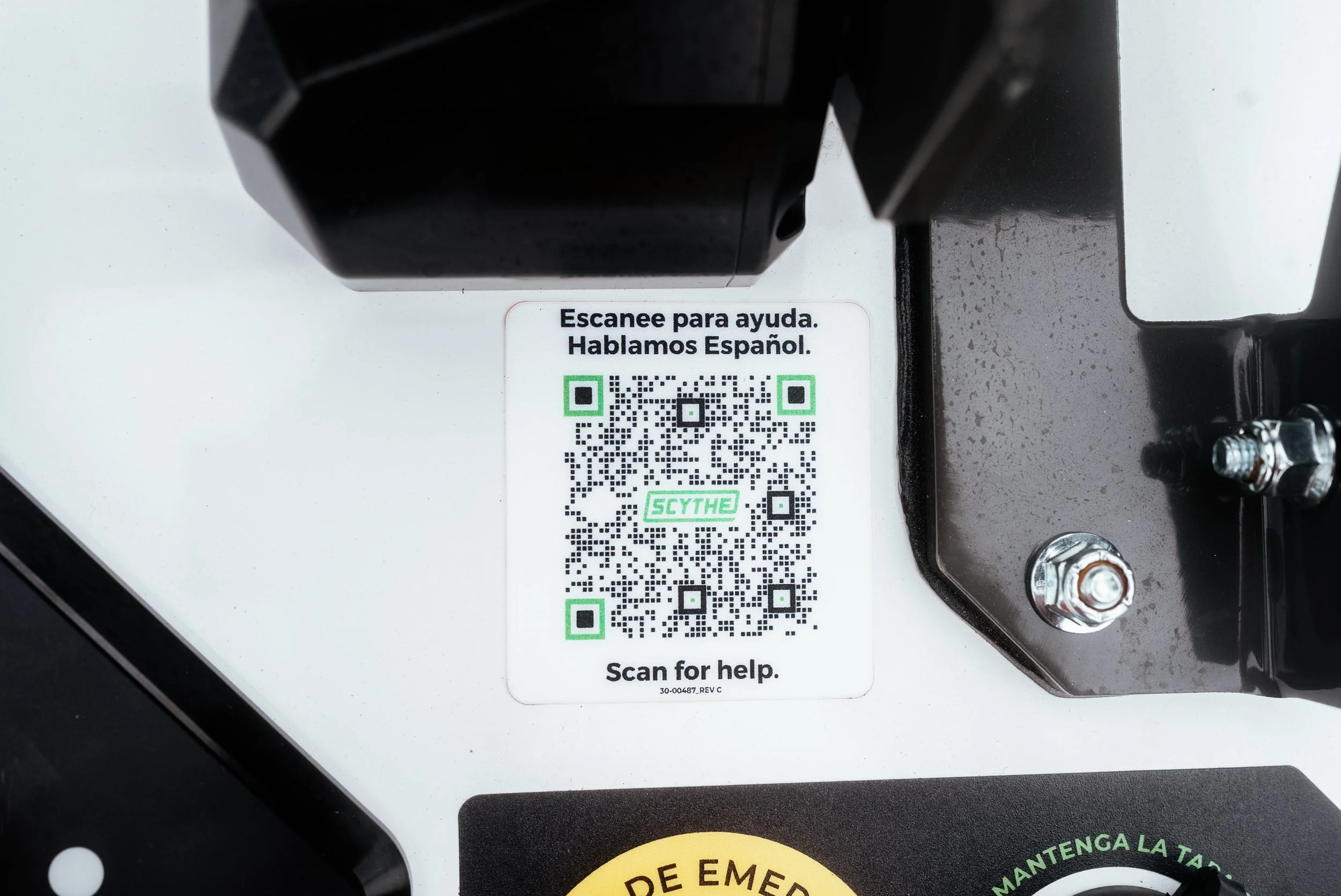 Close-up of the bilingual support QR code and hardware on a Scythe robotic mower