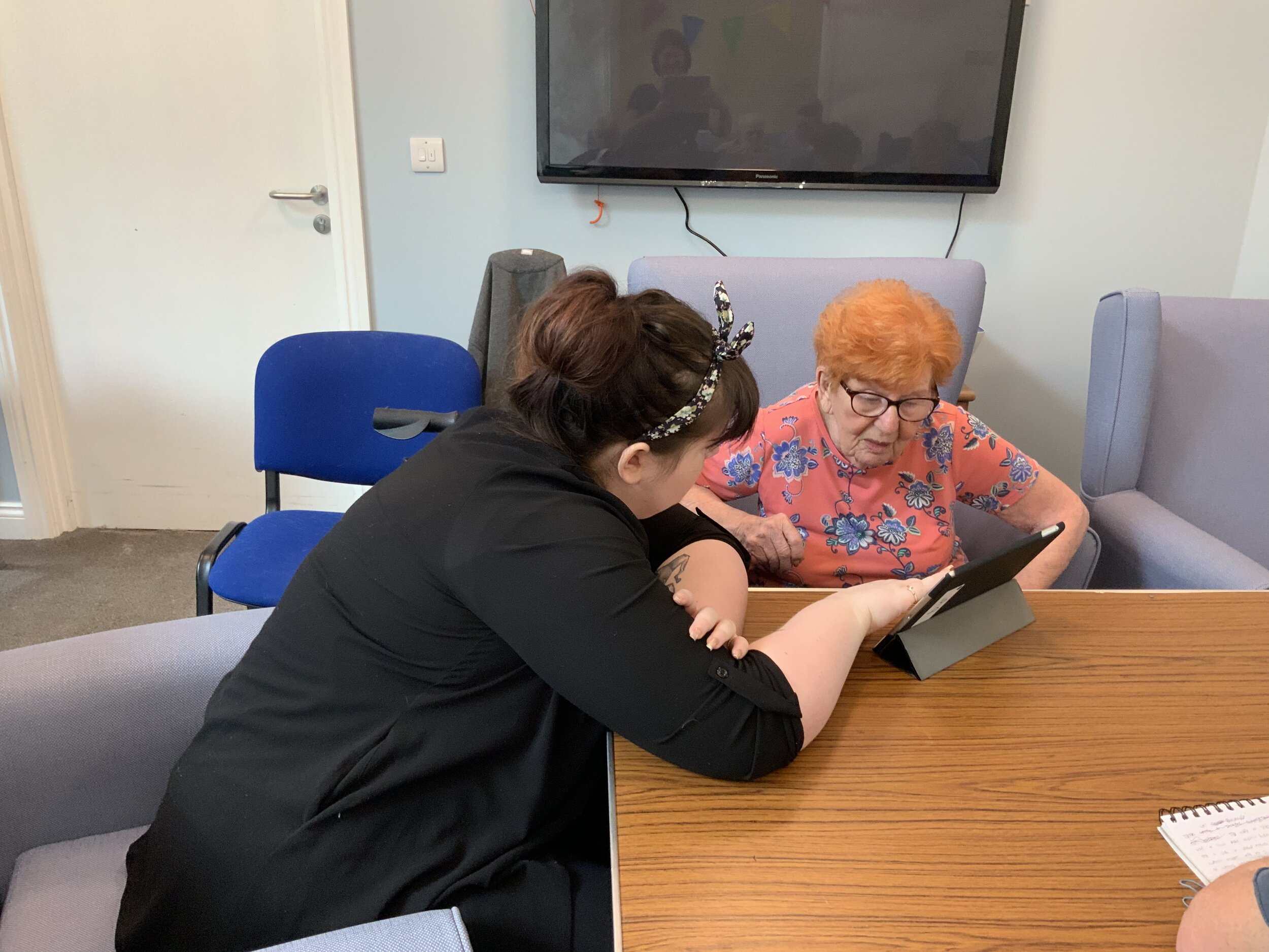 Tutor helping a resident use the ipad to build her lifebook