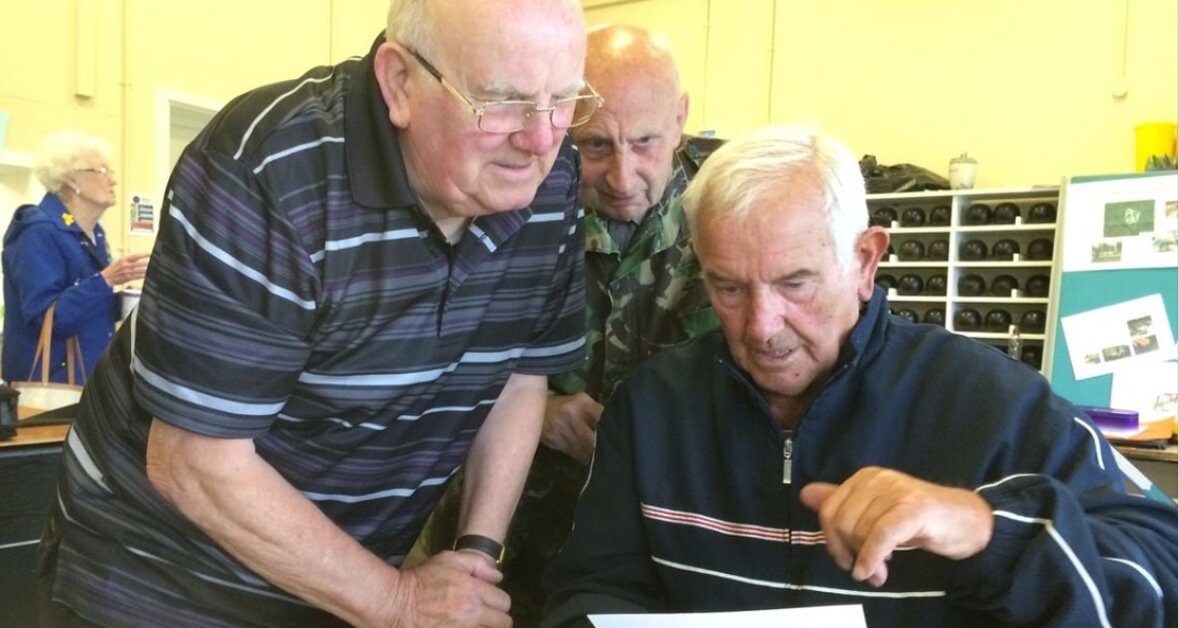 three older men looking through old photos from childhood