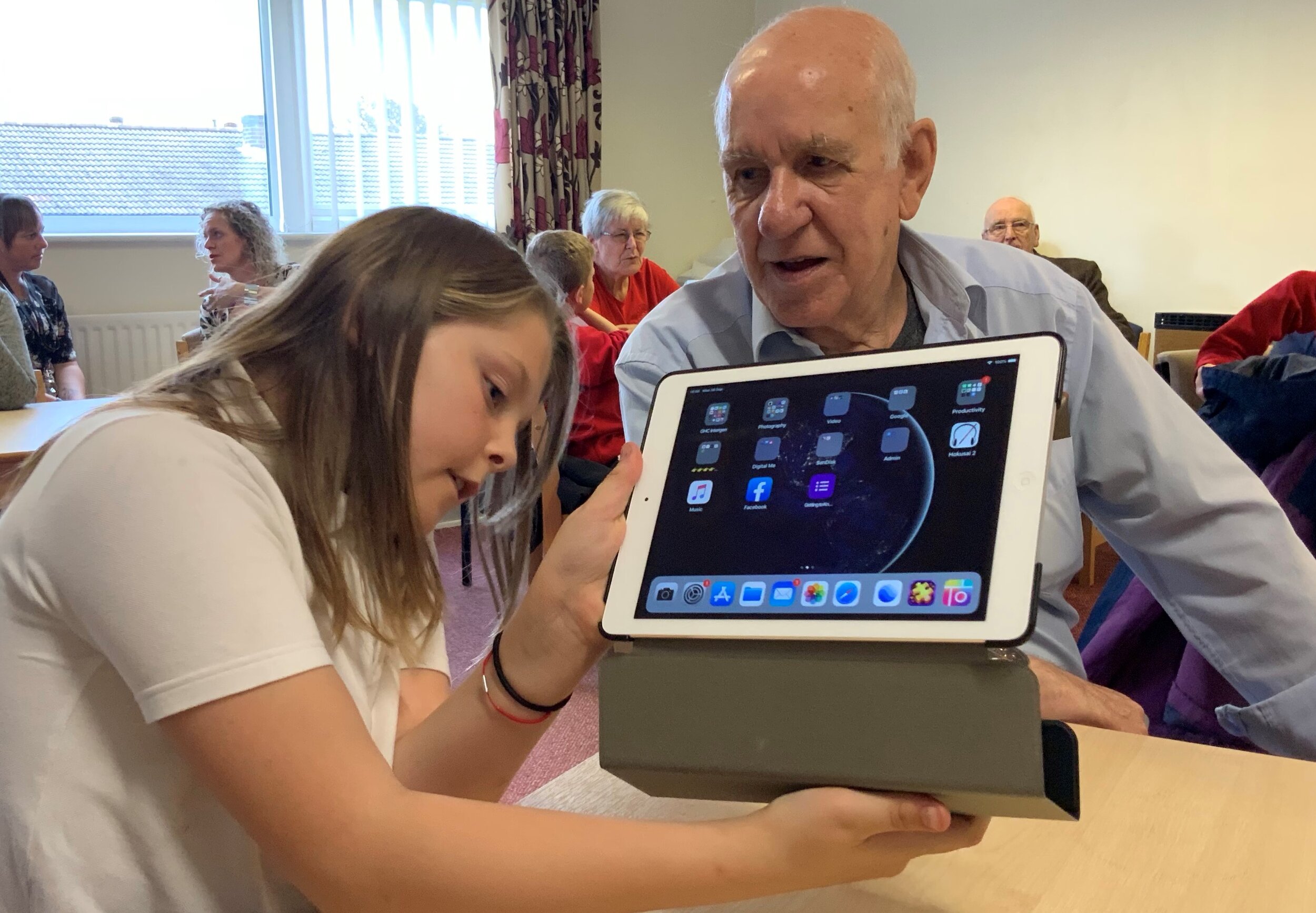 School girl showing an older man how to use the case on the ipad