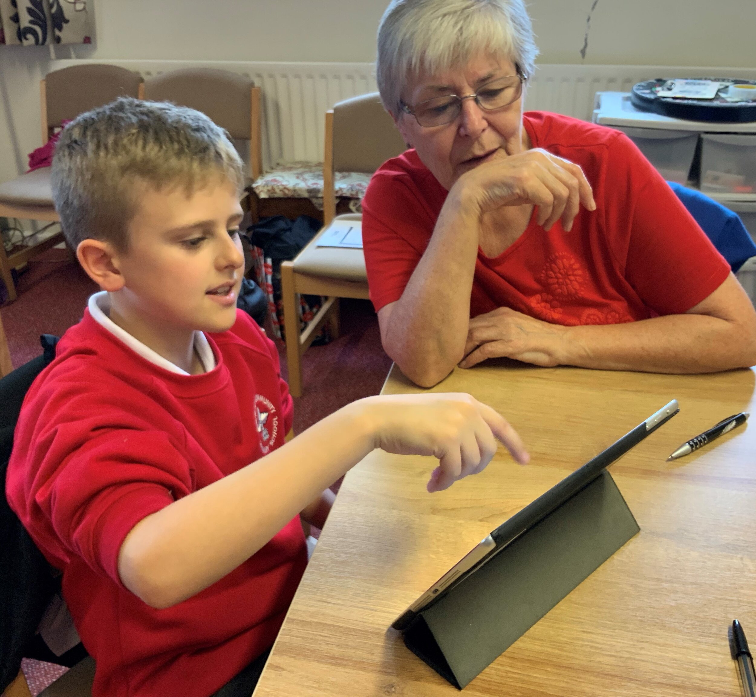 School boy showing older lady how to swipe on the ipad