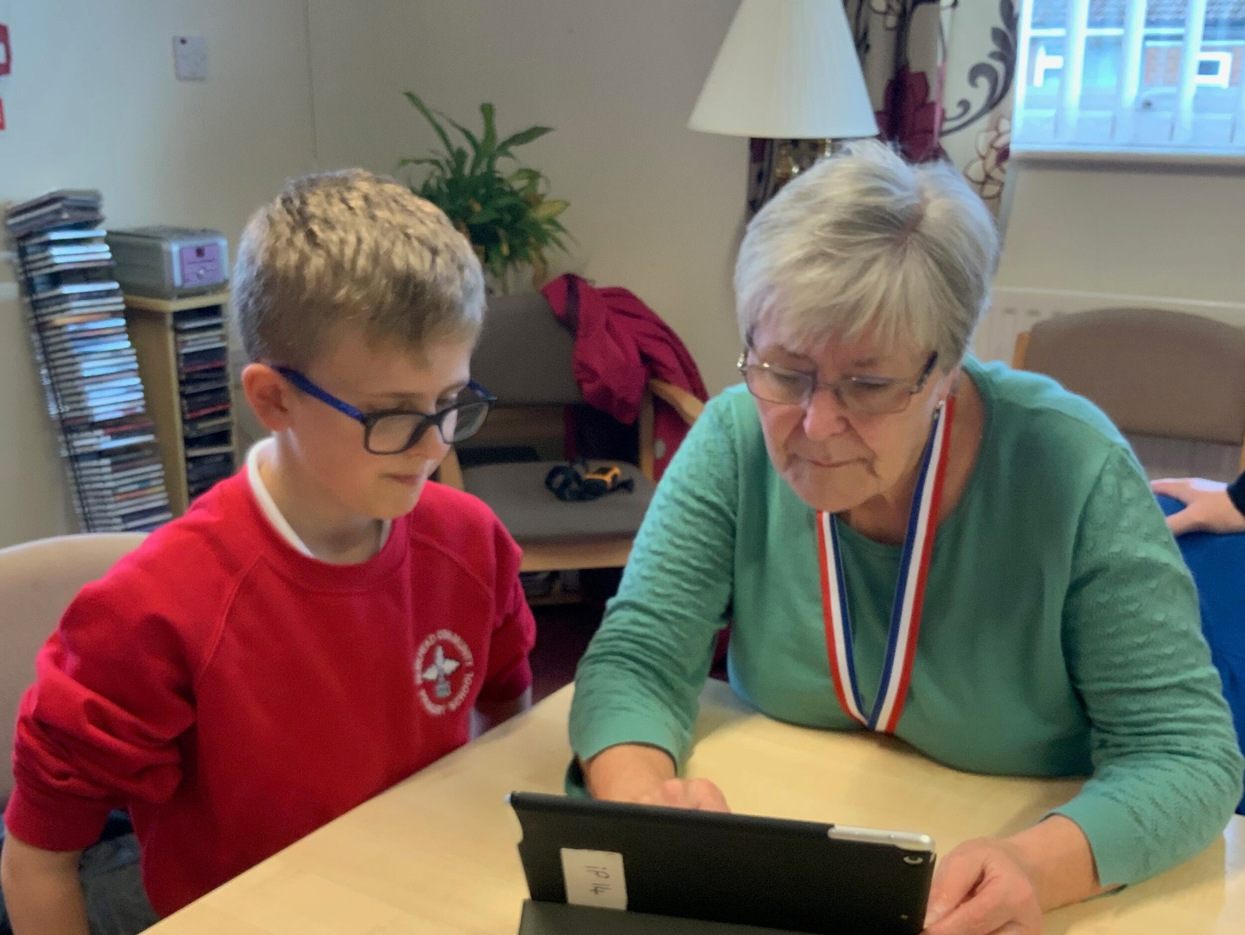 Older women being guided by a young school boy on using the ipads