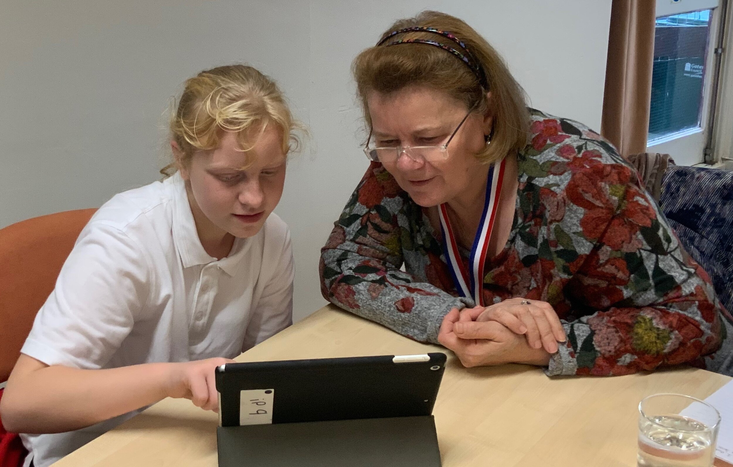 School girl showing her older digital buddy how to use the ipad